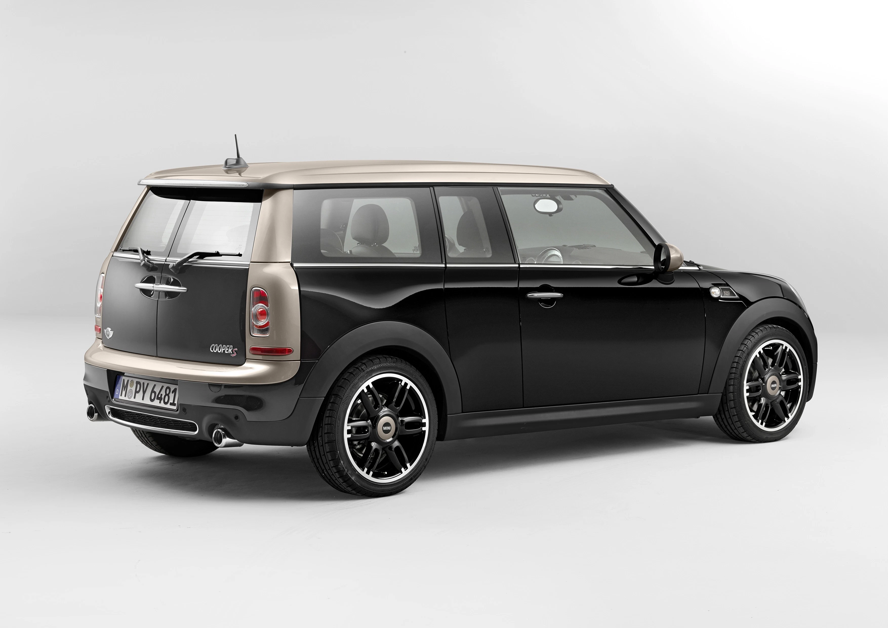 Schwarzer Mini Clubman mit beigem Dach, seitliche Heckansicht. Elegantes Design, moderne Felgen, auf hellem Hintergrund.