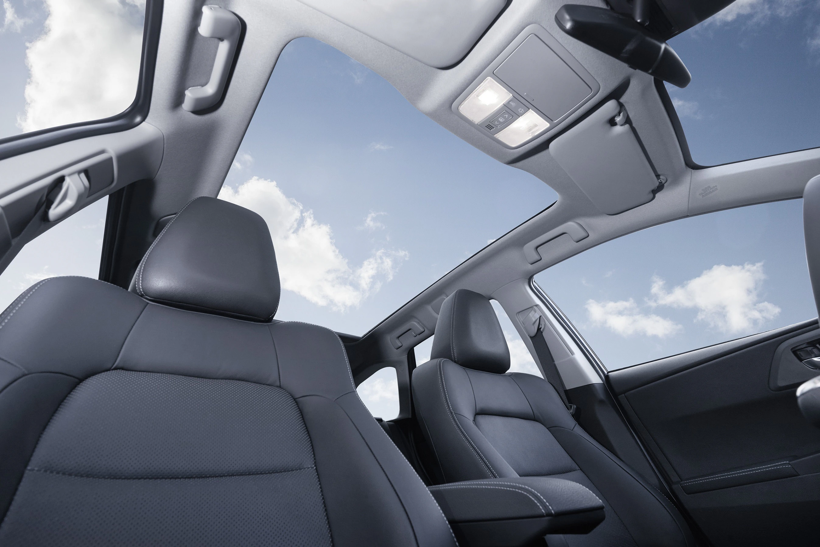Autoinnenraum mit Panoramadach, durch das blauer Himmel und weiße Wolken sichtbar sind. Vorder- und Rücksitze in dunklem Leder.