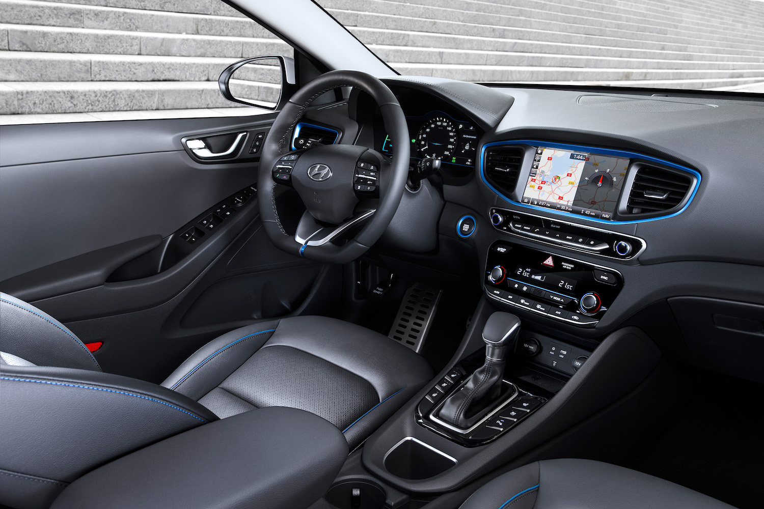 Innenraum eines modernen Autos mit Lederlenkrad, digitalem Armaturenbrett und einem großen Touchscreen-Display auf der Mittelkonsole.