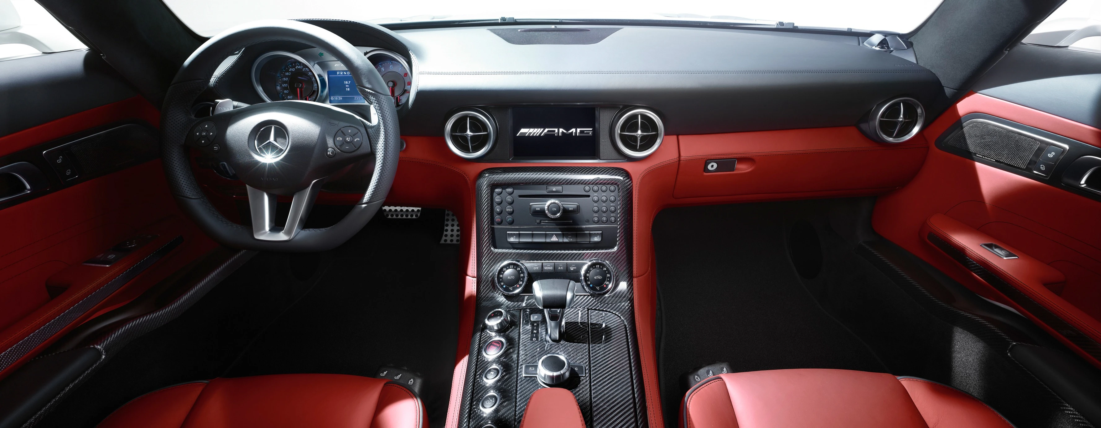 Innenraum eines Mercedes-AMG mit rotem Leder, sportlichem Lenkrad, Lüftungsdüsen im Stil von Turbinen und mittigem Infotainment-Display.