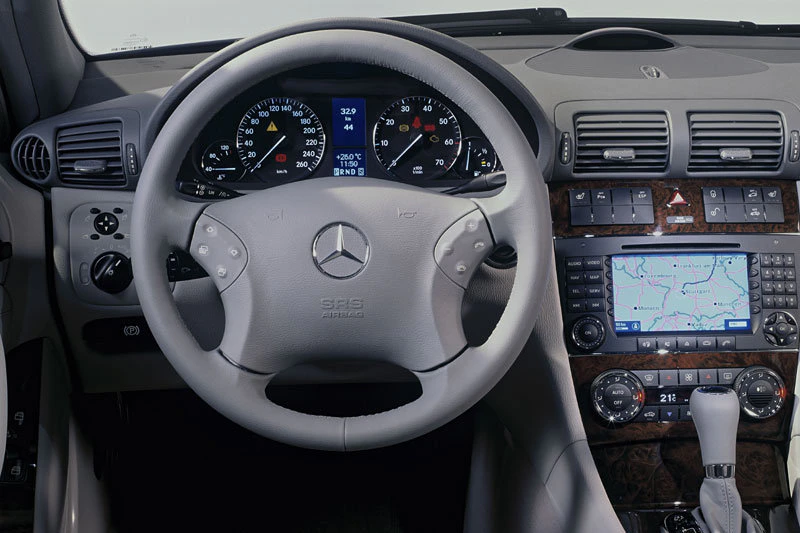 Lenkrad und Armaturenbrett eines Mercedes-Benz mit Tachometer, Navigationssystem und diversen Bedienelementen.