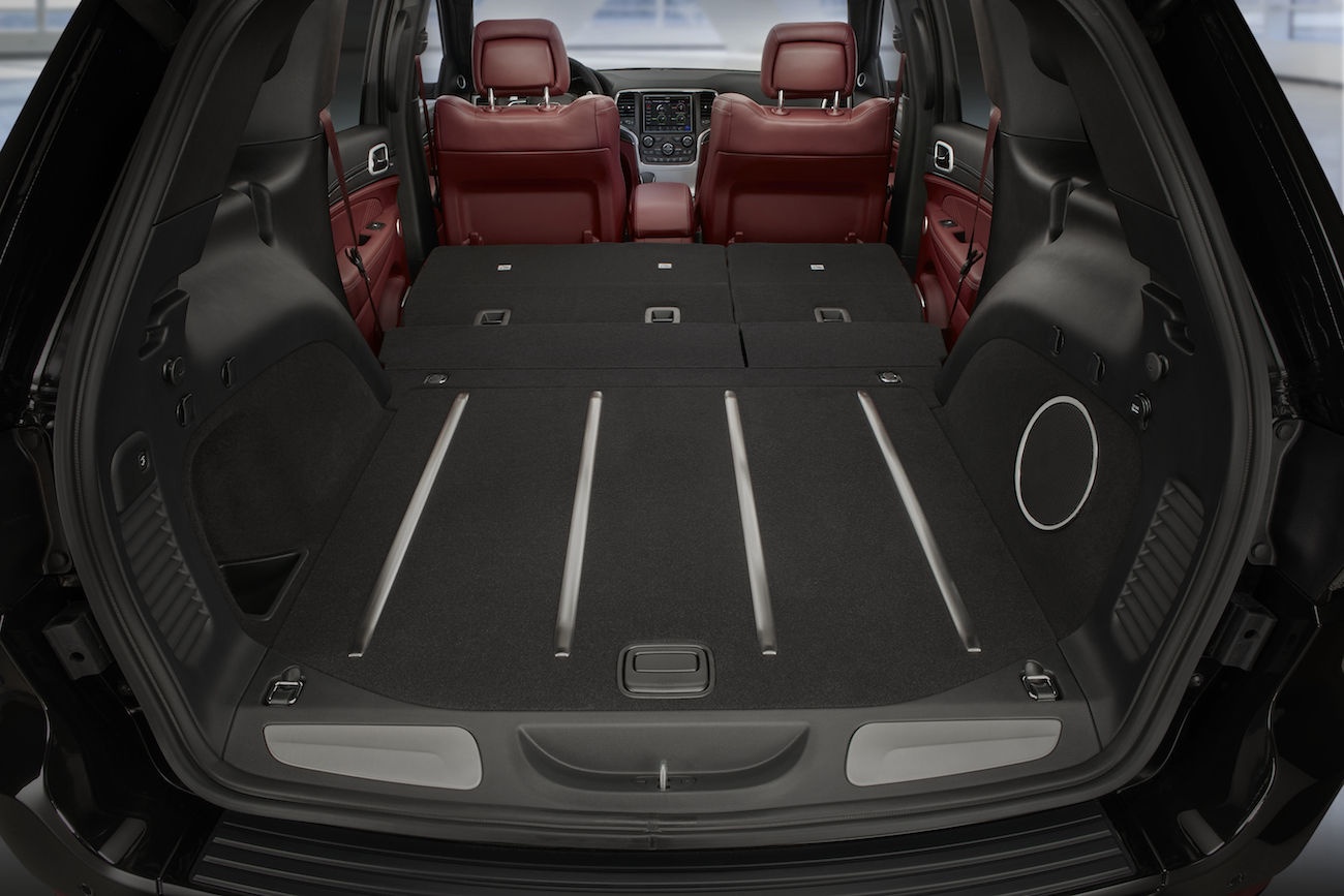 Sicht von hinten in einen SUV mit umgeklappten Rücksitzen, die einen großen, flachen Laderaum mit schwarzen und roten Innenausstattungen zeigen.