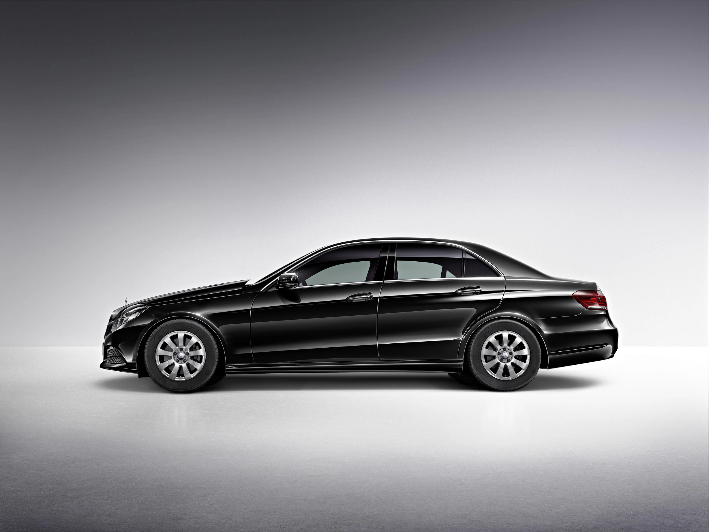 Schwarze Limousine im Profil, seitlich vor neutralem Hintergrund fotografiert. Elegantes Design und glänzende Oberfläche.