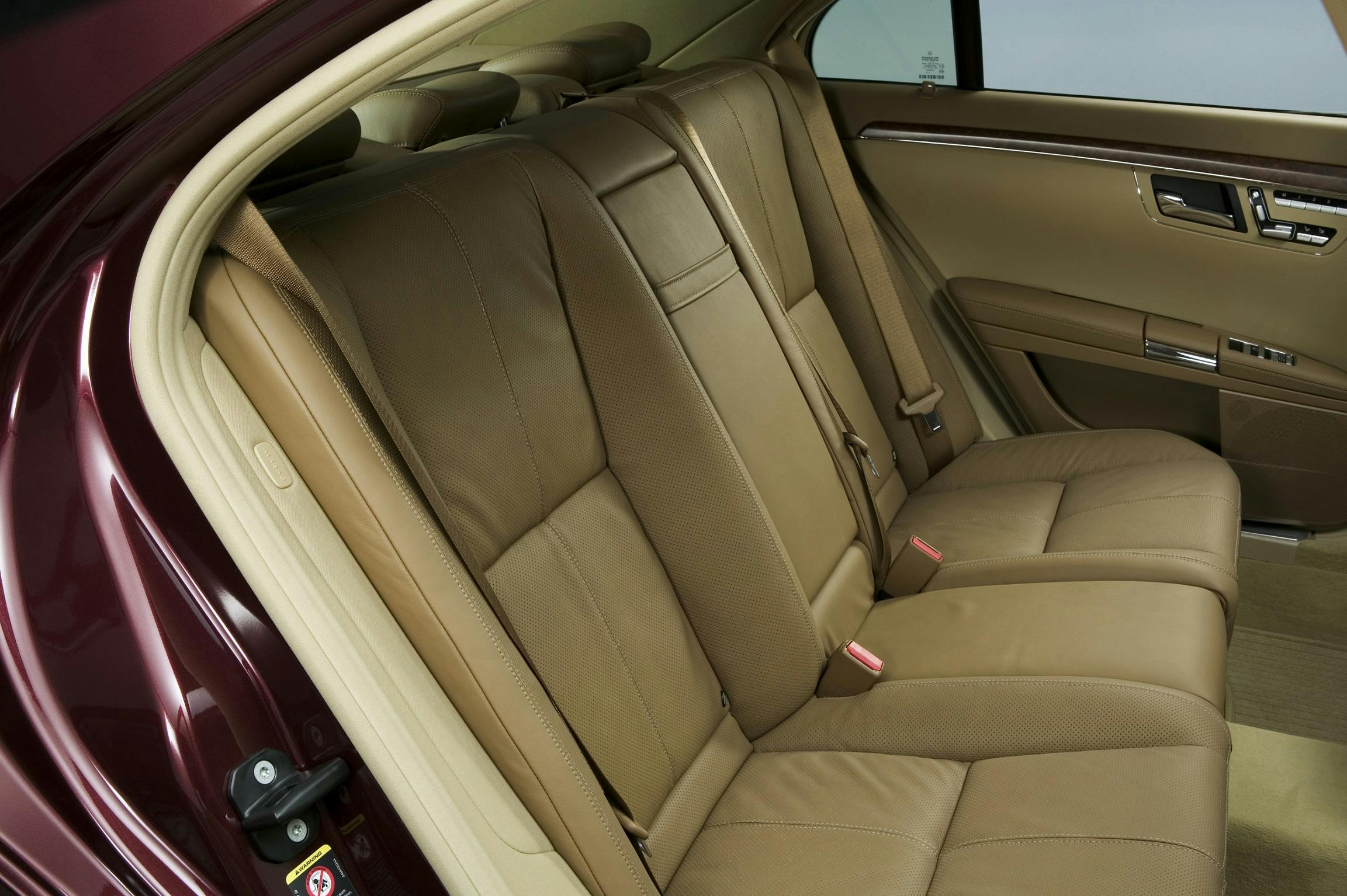 Beige Ledersitze auf der Rückbank eines Autos, Tür geöffnet, hochwertige Innenausstattung sichtbar.