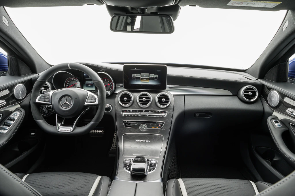 Innenraum eines Mercedes-Benz mit modernem Armaturenbrett, Lederlenkrad, Touchscreen-Display und eleganten Designelementen.