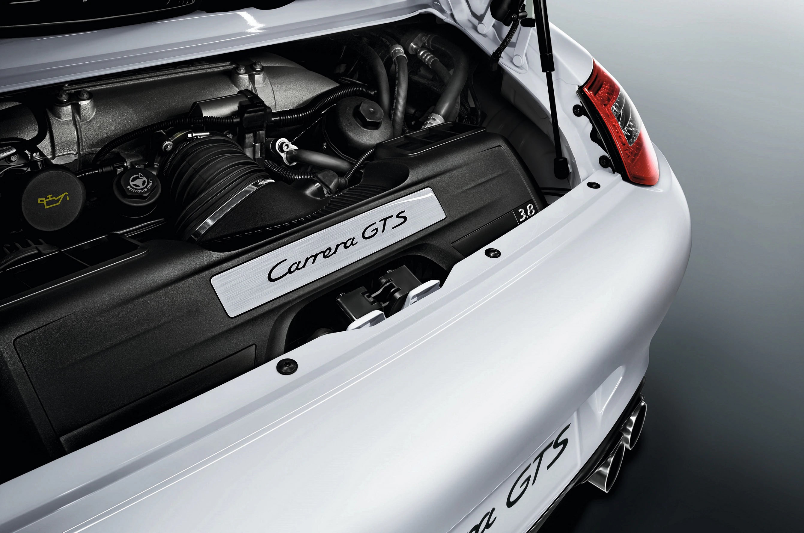 Motorraum eines Porsche Carrera GTS in Nahaufnahme, zeigt den Motor und den „Carrera GTS” Schriftzug auf einem schwarzen Abdeckteil.