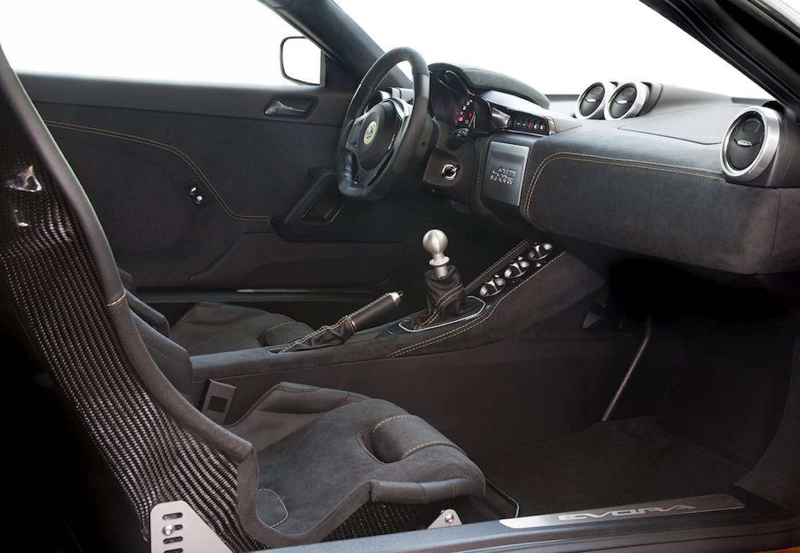 Innenraum eines Sportwagens mit schwarzem Interieur, Schalensitzen und manuellem Schaltgetriebe. Moderne Instrumententafel und Lenkrad.