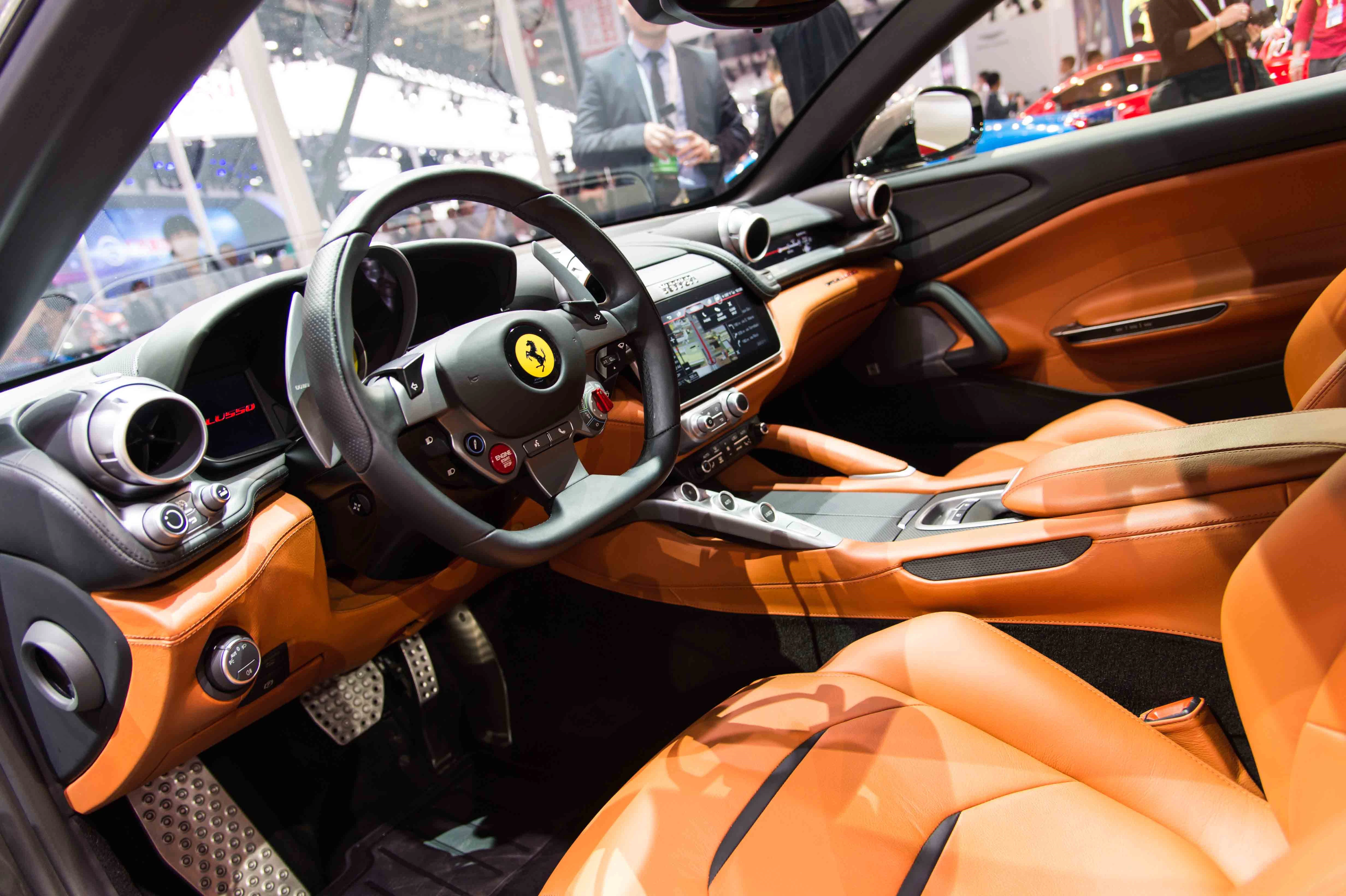 Innenansicht eines Luxusautos mit orangenen Ledersitzen, einem modernen Lenkrad und einem digitalen Armaturenbrett.