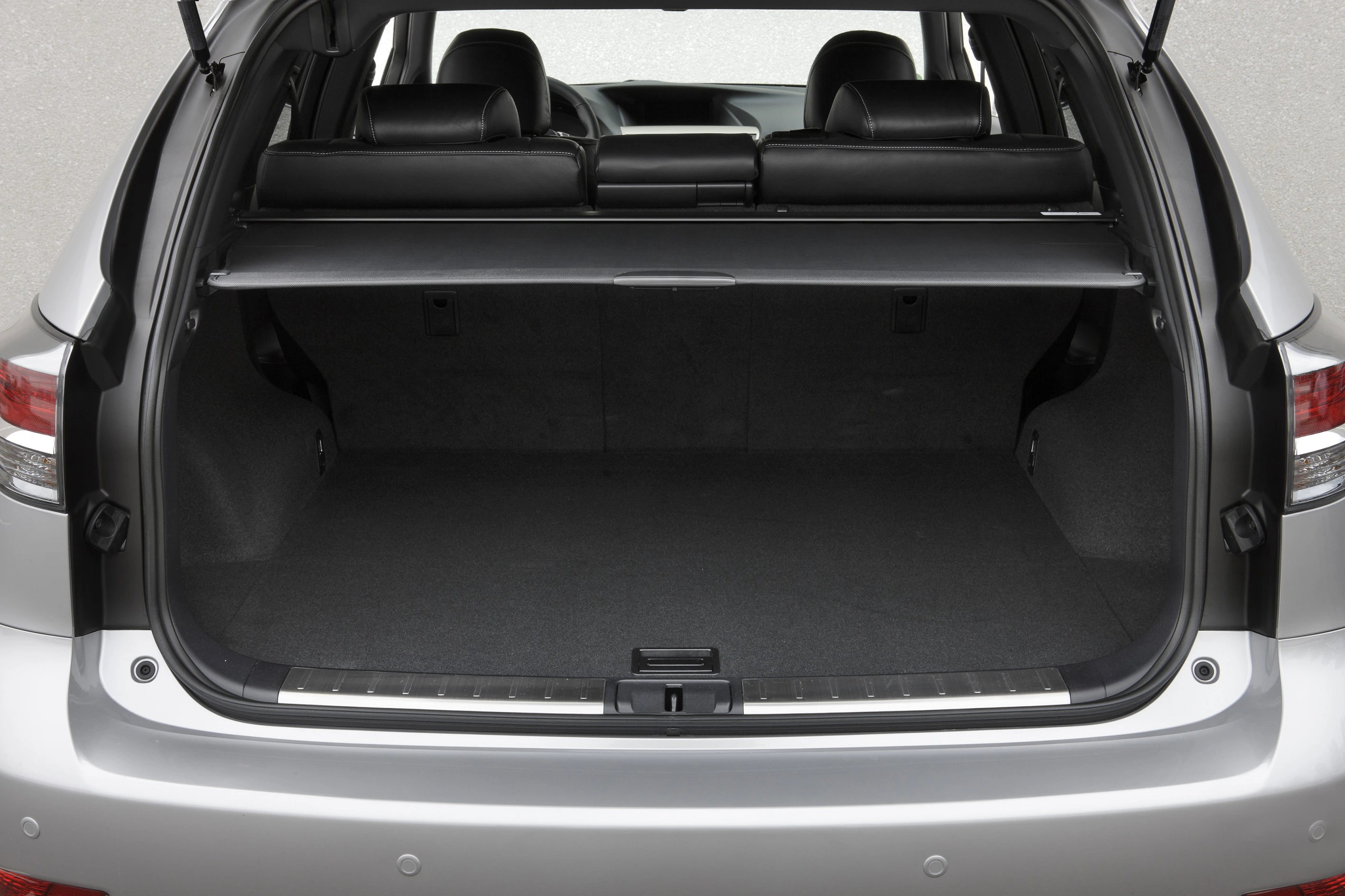 Offener Kofferraum eines silbernen Autos, leer mit hochgeklappter Heckklappe und schwarzen Rücksitzen im Hintergrund.