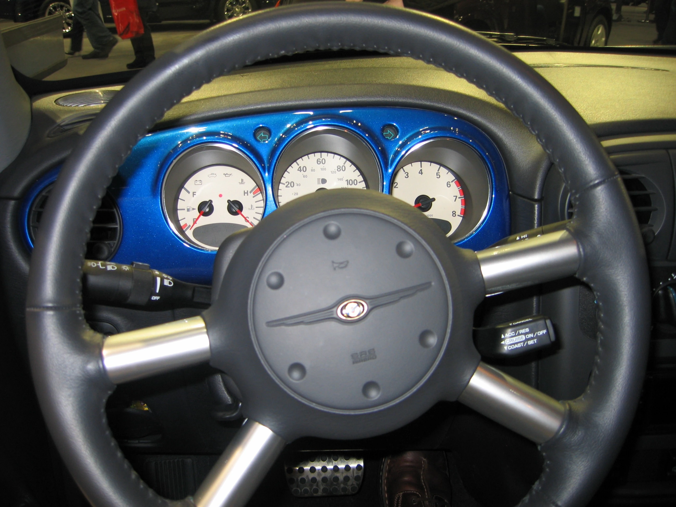 Lenkrad und Armaturenbrett eines Autos mit blauer Verkleidung und klassischen Rundinstrumenten.
