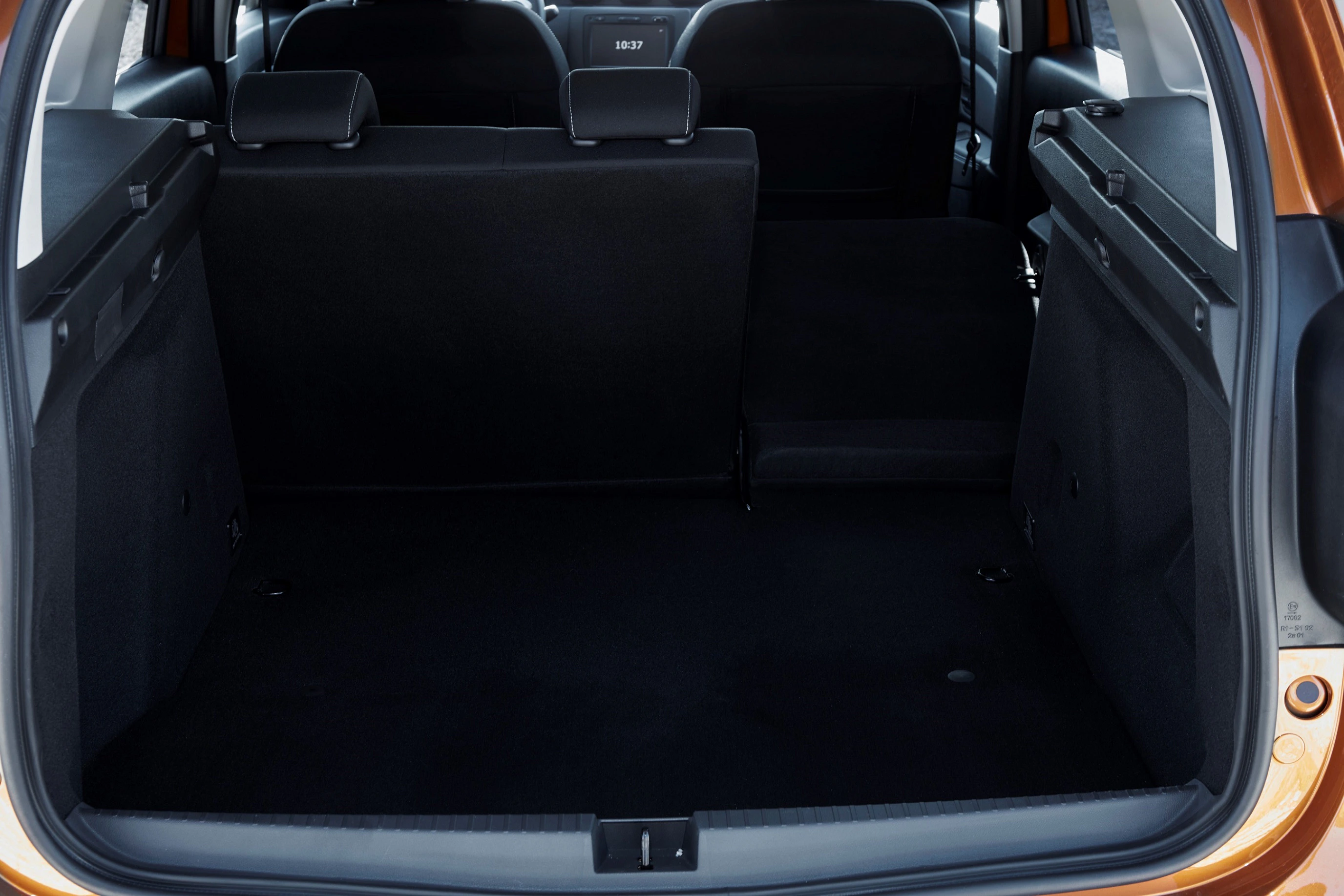 Kofferraum eines Autos mit umgeklappter Rücksitzbank, die mehr Ladefläche bietet. Die Innenausstattung ist dunkel gehalten.