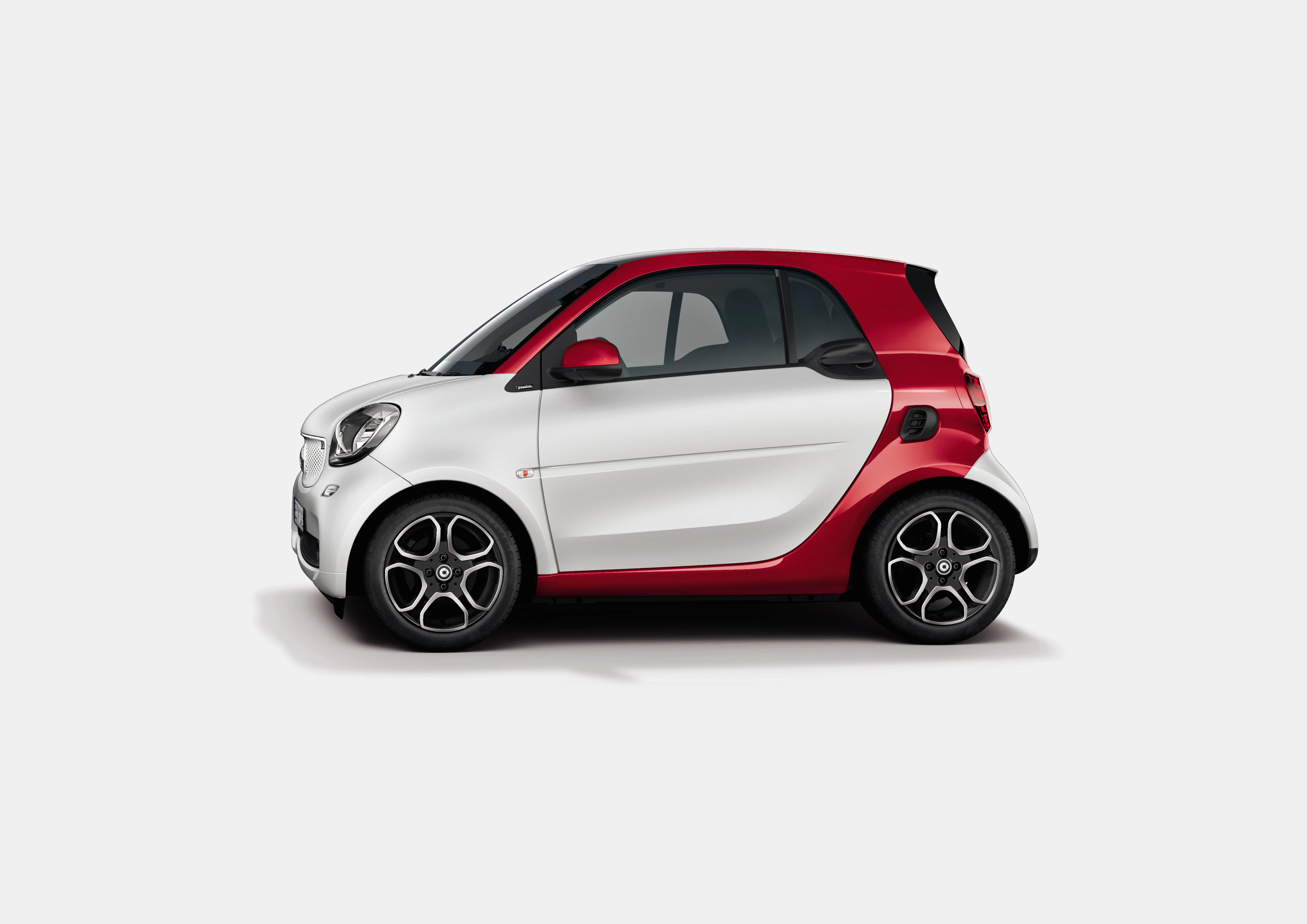 Kleines, zweifarbiges Auto, weiß mit rotem Akzent, seitliche Ansicht auf grauem Hintergrund.