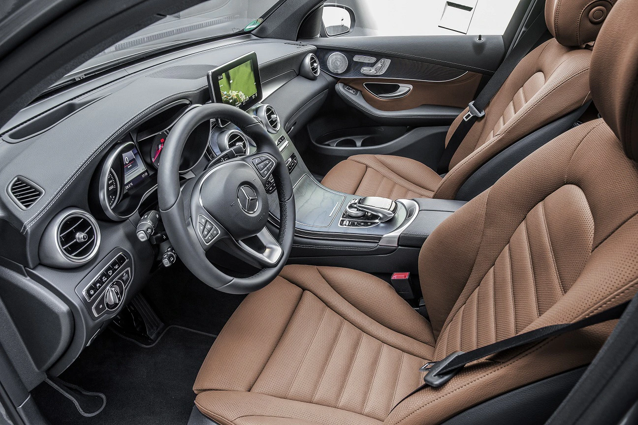 Innenraum eines modernen Autos mit braunen Ledersitzen, einem digitalen Armaturenbrett und einem zentralen Infotainment-Bildschirm.