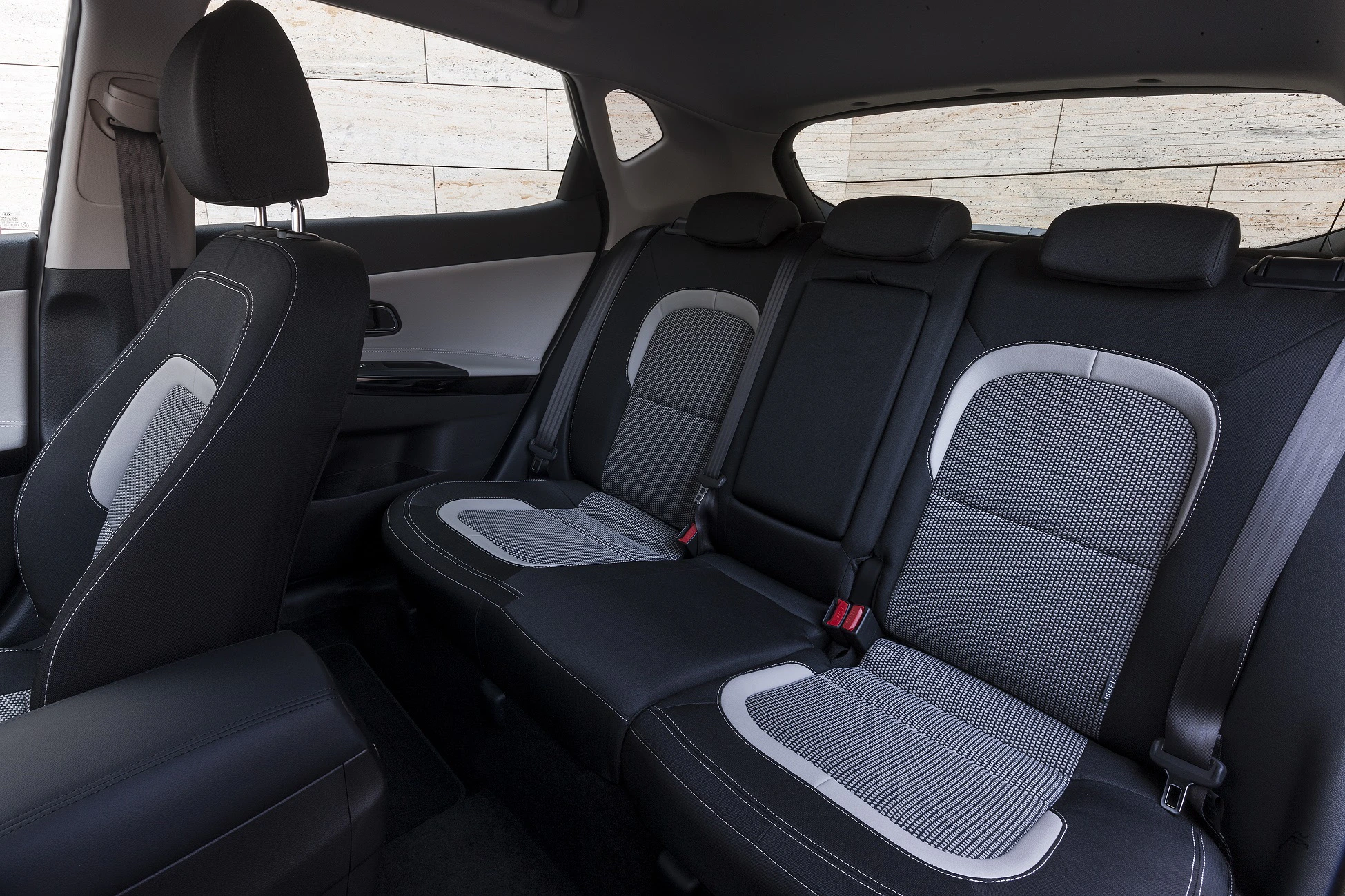 Rücksitze eines Autos mit grauen und schwarzen Polstern, hervorgehobene Kopfstützen und Sicherheitsgurte, modernes Interieurdesign.