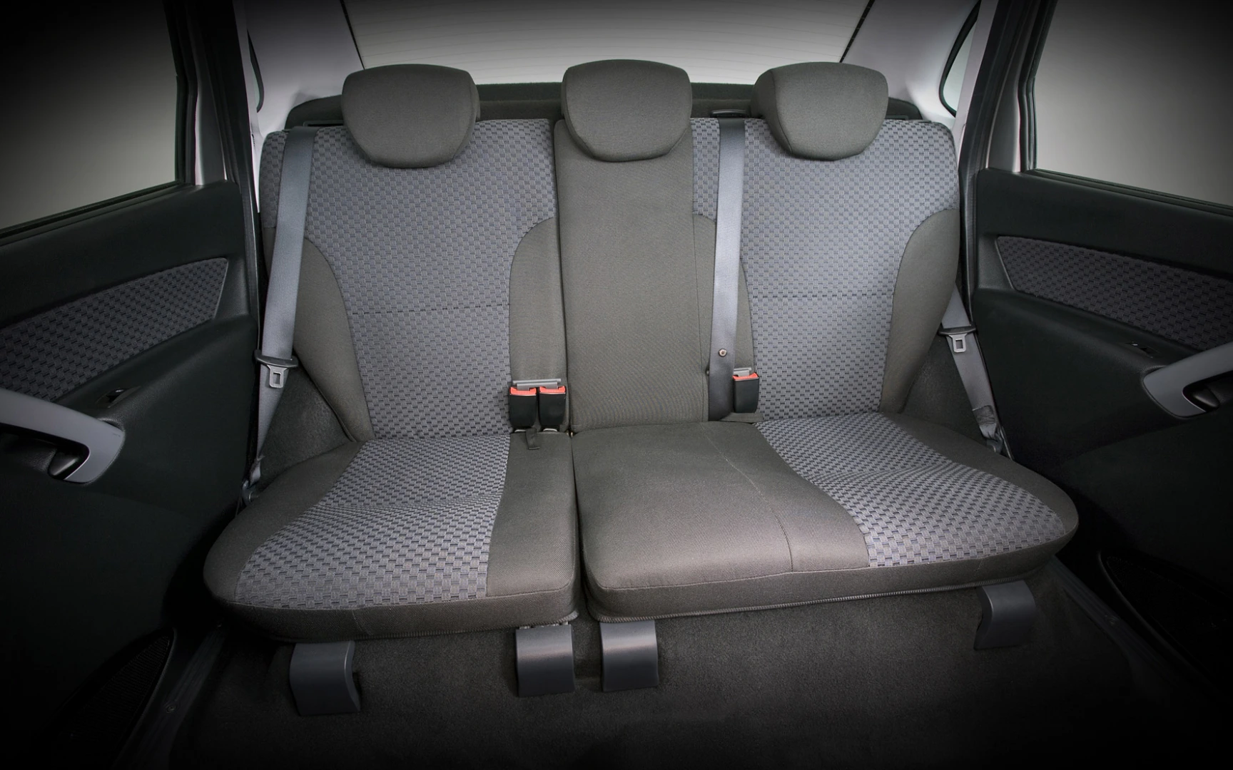 Rückbank eines Autos mit drei Sitzen, schwarzen Kopfstützen und grauen Sitzbezügen in einem modernen Fahrzeuginterieur.