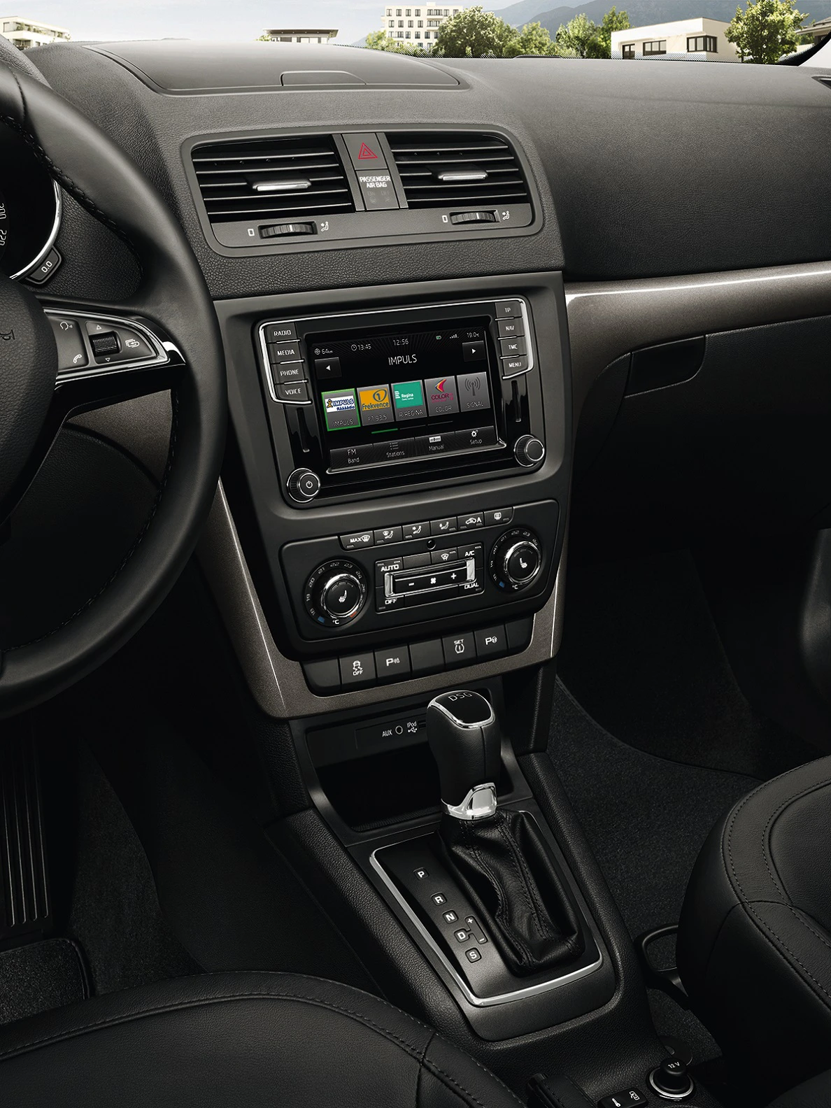 Innenraum eines Autos mit Mittelkonsole; zeigt ein Infotainmentsystem mit Display, Klimaregler und Automatik-Schaltknüppel.