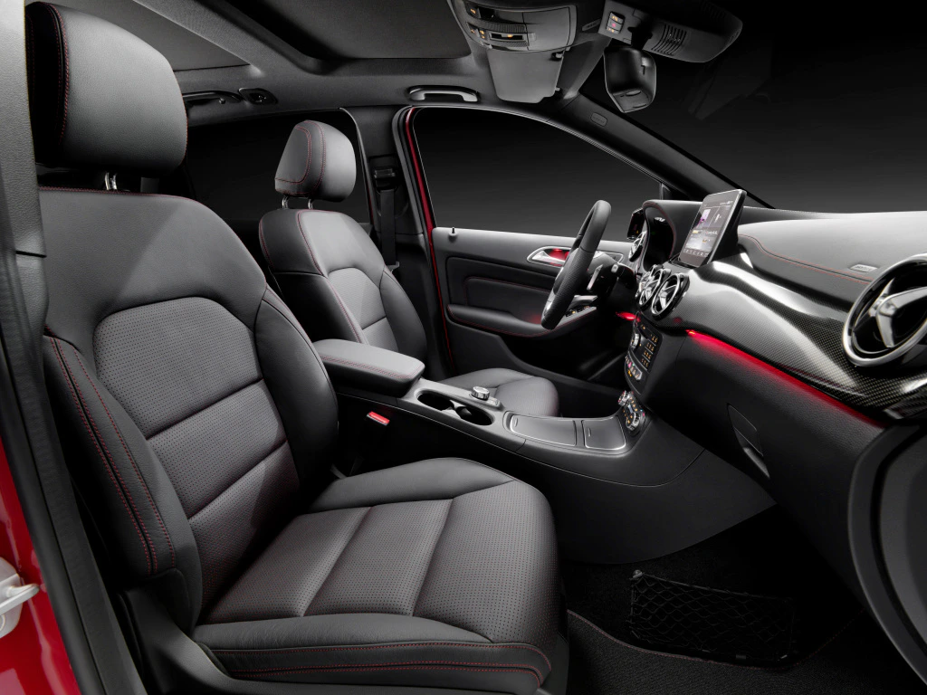 Innenraum eines modernen Autos mit schwarzen Ledersitzen, einem zentralen Bildschirm und einem sportlichen, eleganten Design in Rot und Schwarz.