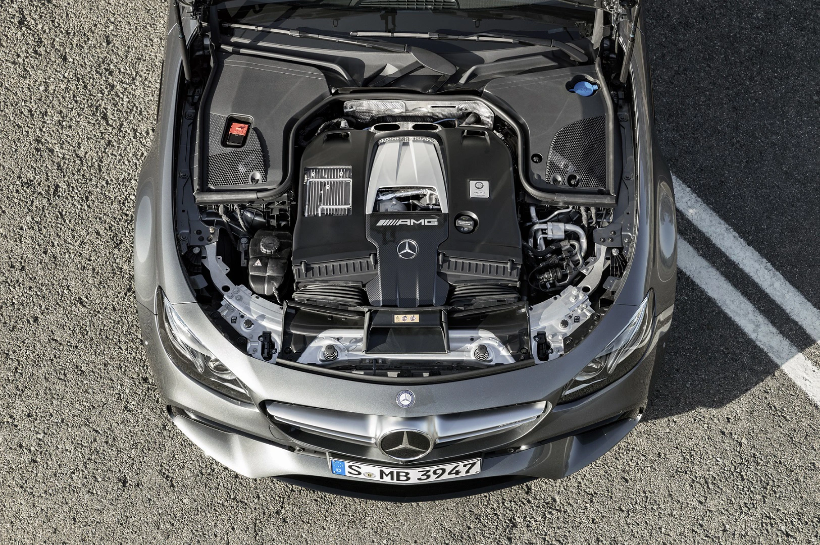 Motorraum eines Mercedes-Benz AMG mit geöffneter Motorhaube, dargestellt von oben. Sichtbar ist der leistungsstarke Motorblock.