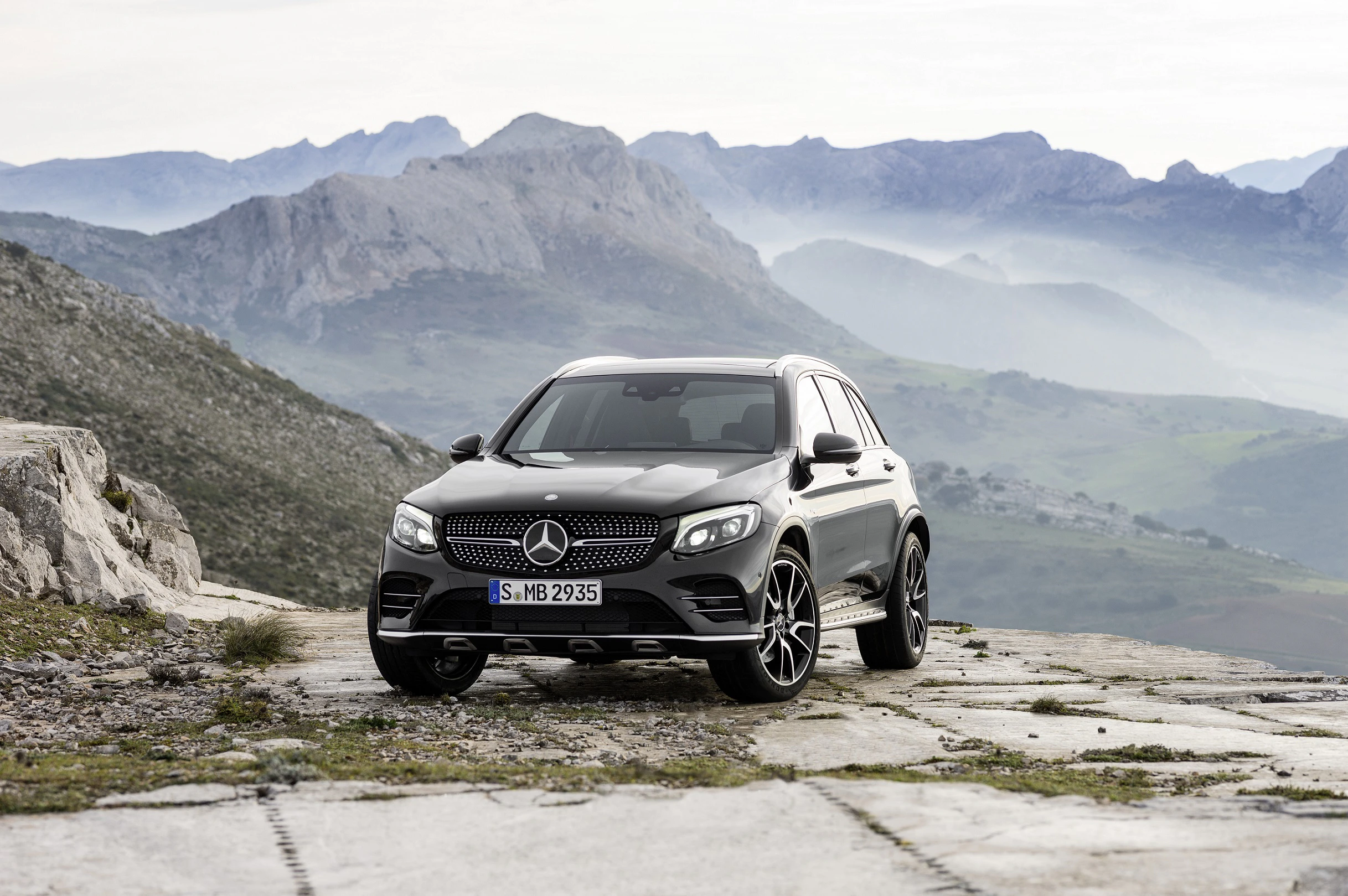 Ein grauer Mercedes-Benz SUV steht auf einer Felsplatte, umgeben von einer Berglandschaft im Hintergrund.