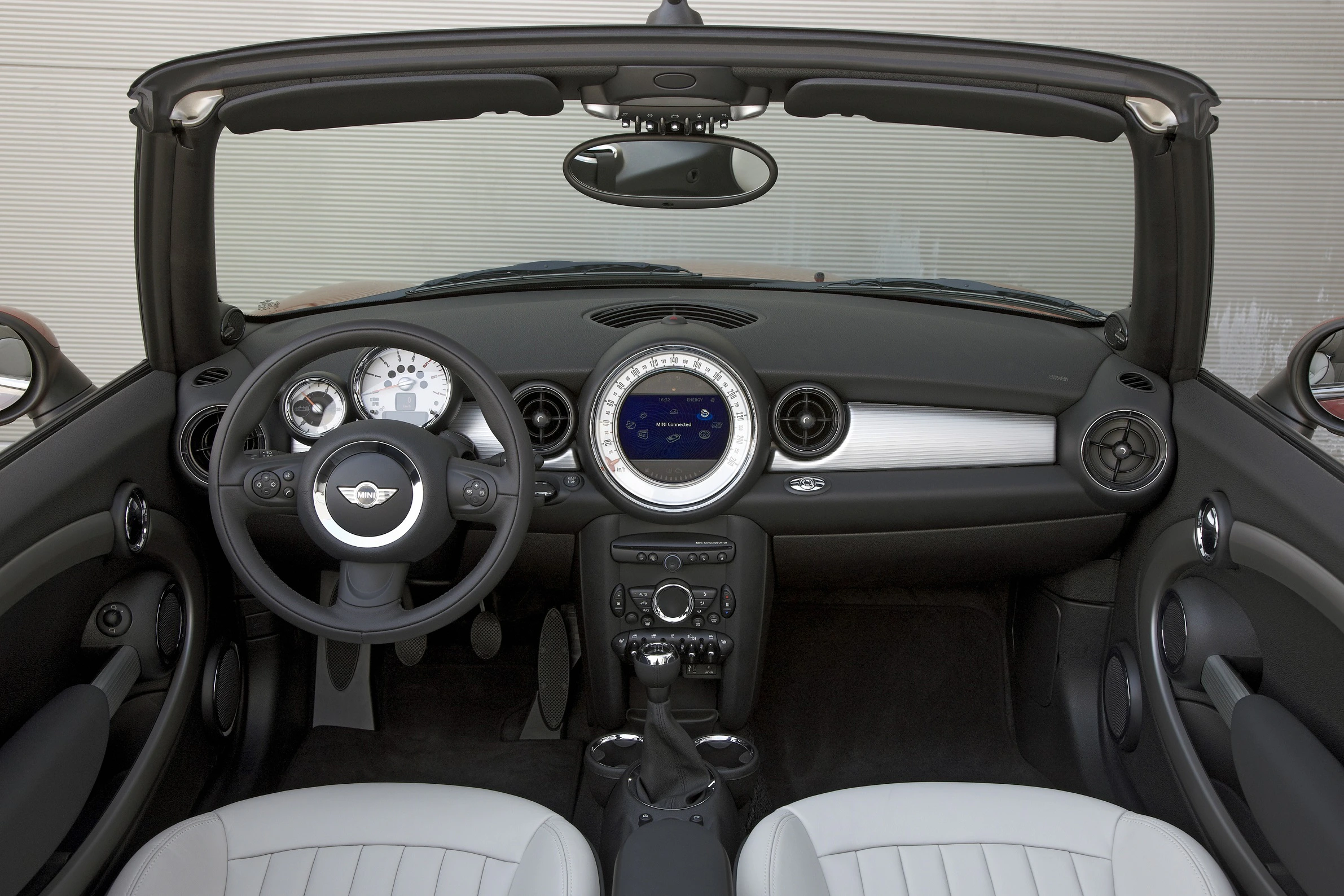 Innenraum eines Autos mit zweifarbigem Lenkrad, weißem Tachometer und modernem Armaturenbrett, schwarze und weiße Sitze.