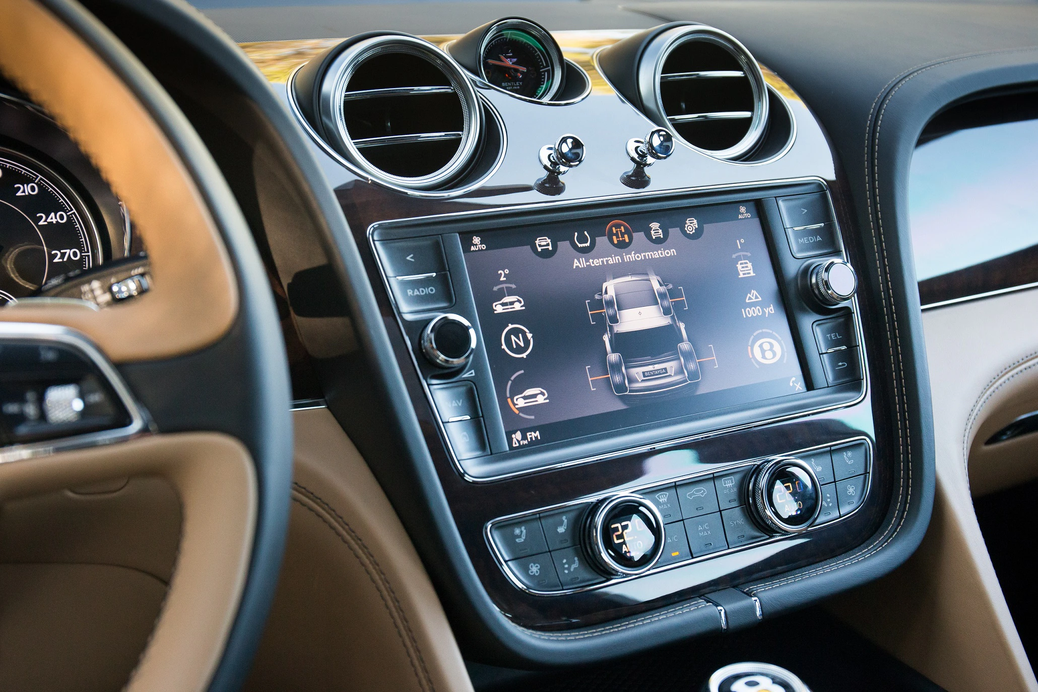 Nahaufnahme eines luxuriösen Auto-Armaturenbretts mit Touchscreen-Display, Lüftungsdüsen und braunen Lederverkleidungen.