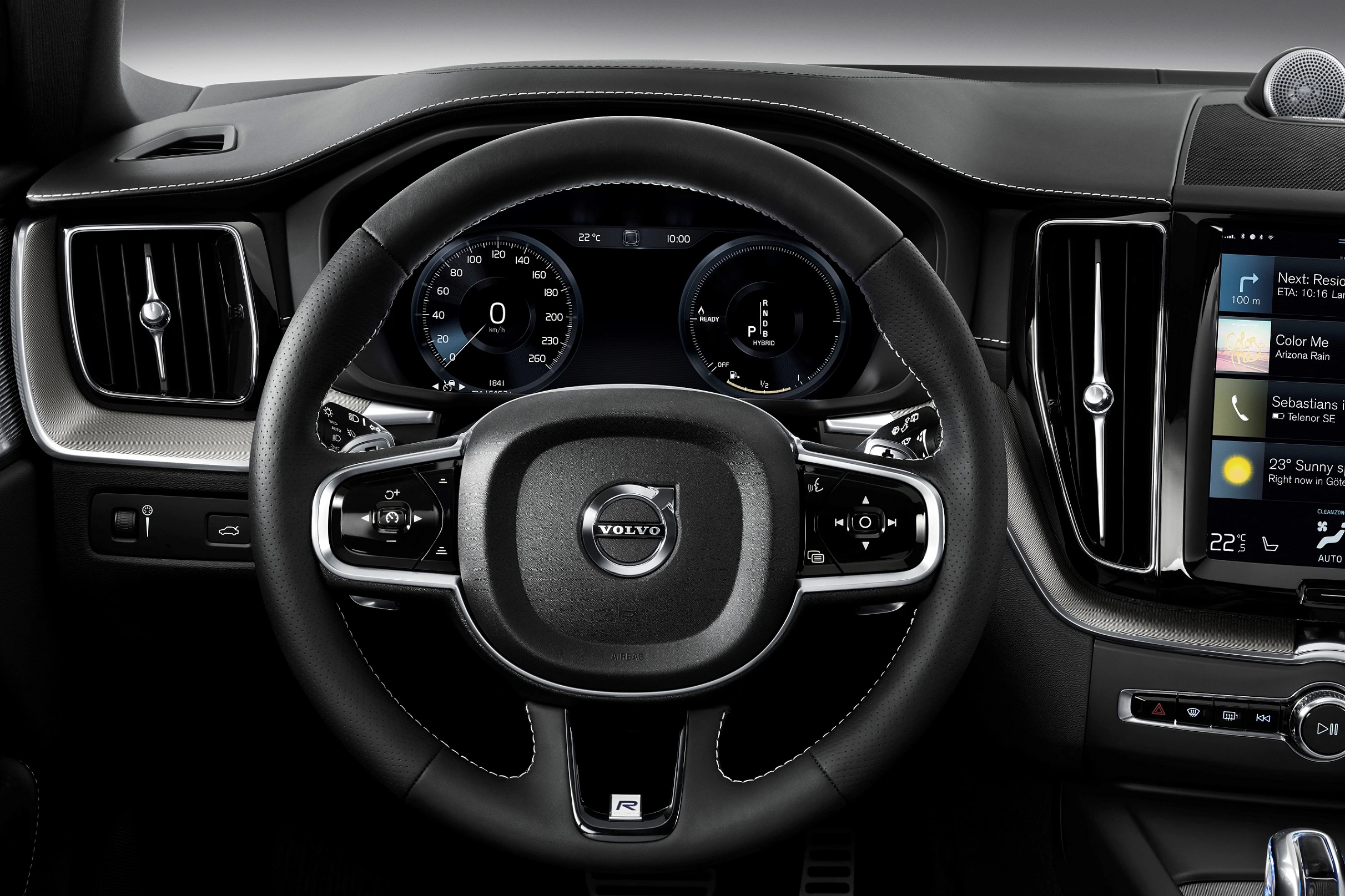 Lenkrad eines Volvo-Autos mit digitalen Anzeigen und Multimedia-Bildschirm. Lederinterieur und moderne Fahrzeugbedienung sichtbar.