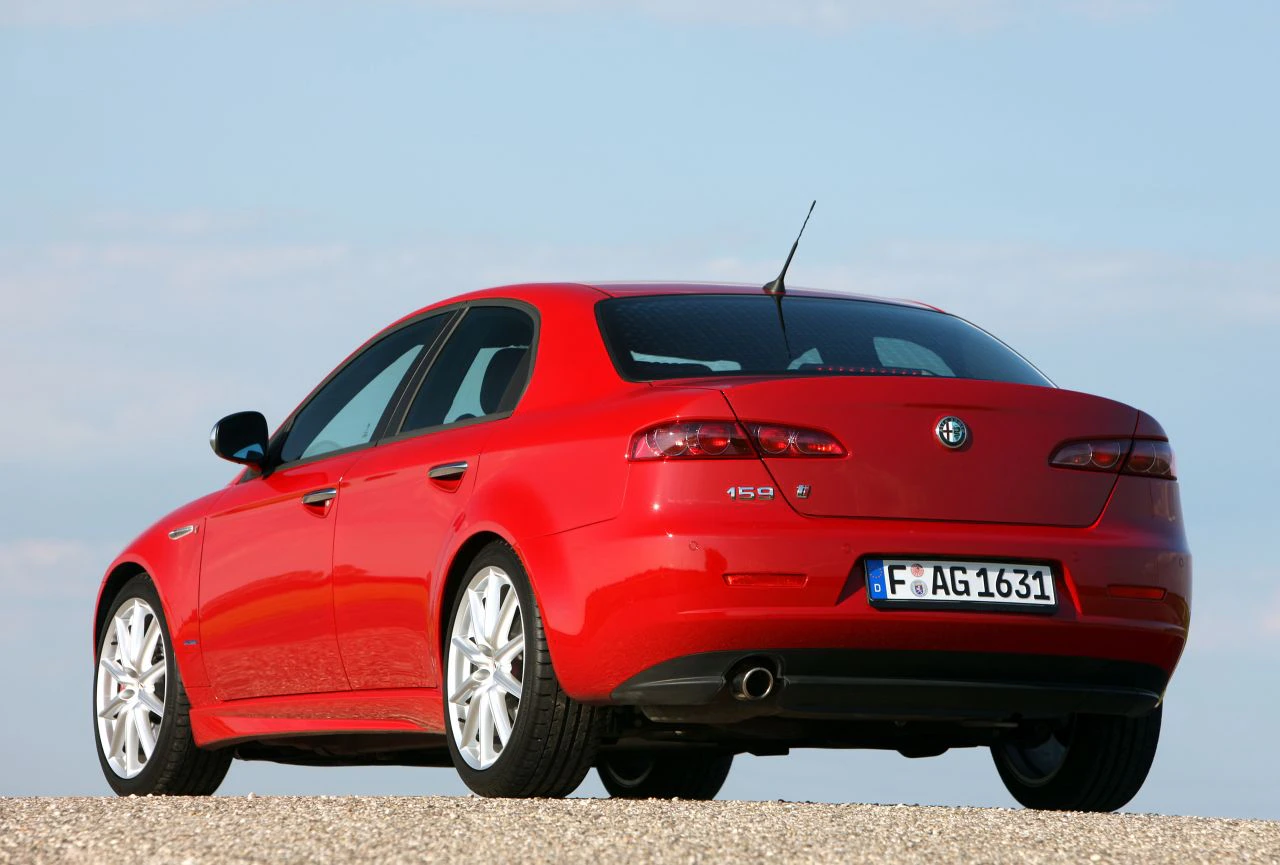 Roter Alfa Romeo 159, Heckansicht, auf einer Straße unter blauem Himmel geparkt.