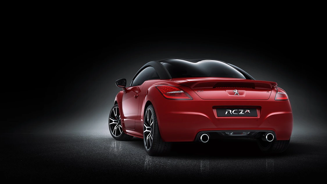 Roter Sportwagen mit elegantem Design, dunklem Hintergrund, beleuchtet von hinten. Das Nummernschild zeigt "RCZ".