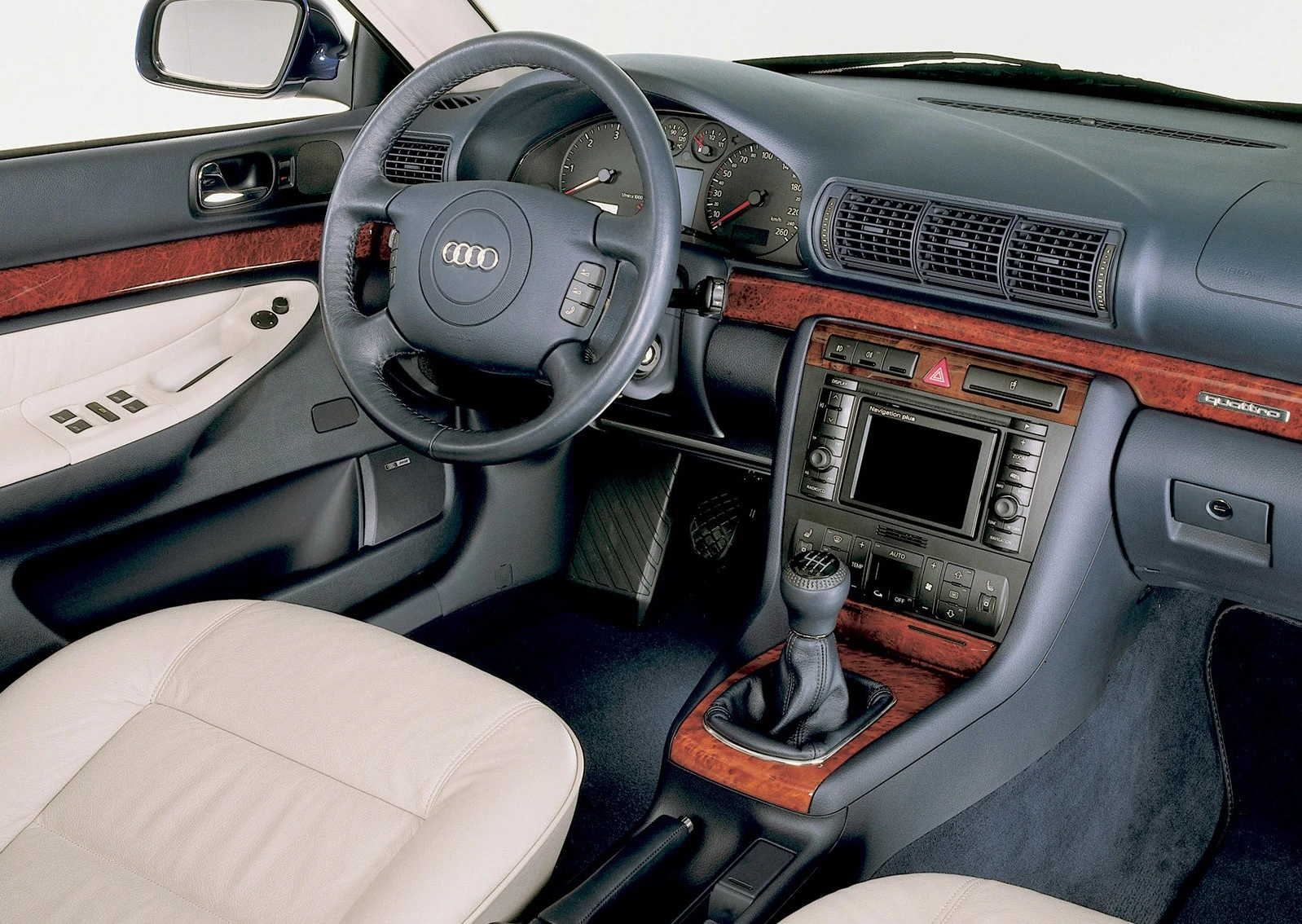 Innenraum eines Audi-Autos mit Lederpolstern, Holzverkleidung, Lenkrad mit Audi-Logo und Schaltknüppel.