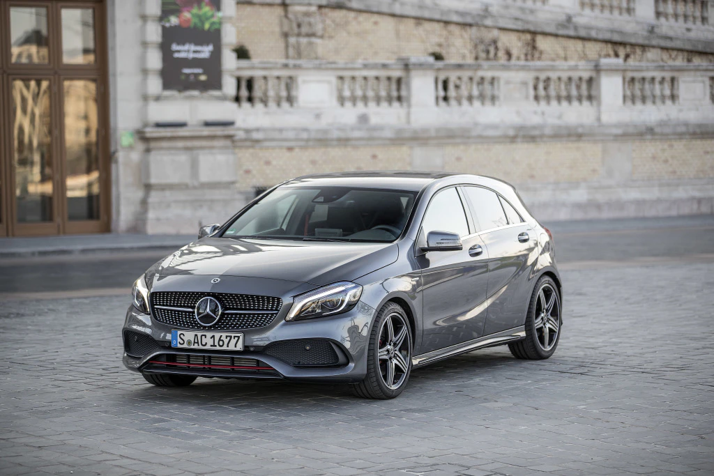 Silberner Mercedes-Benz A-Klasse parkt auf einer gepflasterten Straße vor einem historischen Gebäude.