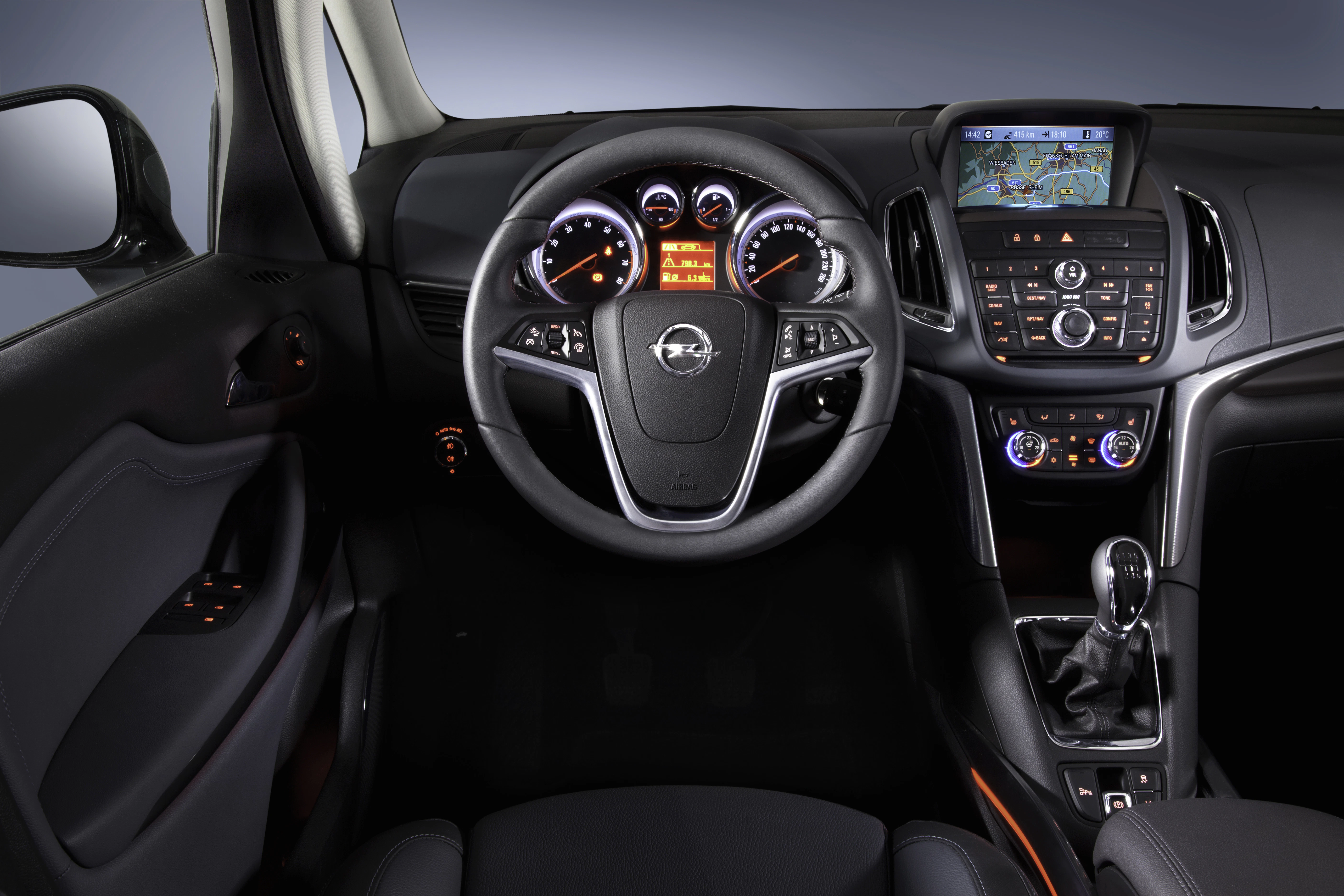 Innenraum eines Autos mit einem Multifunktionslenkrad, Armaturenbrett mit Rundinstrumenten und einem Display mit Navigationssystem.