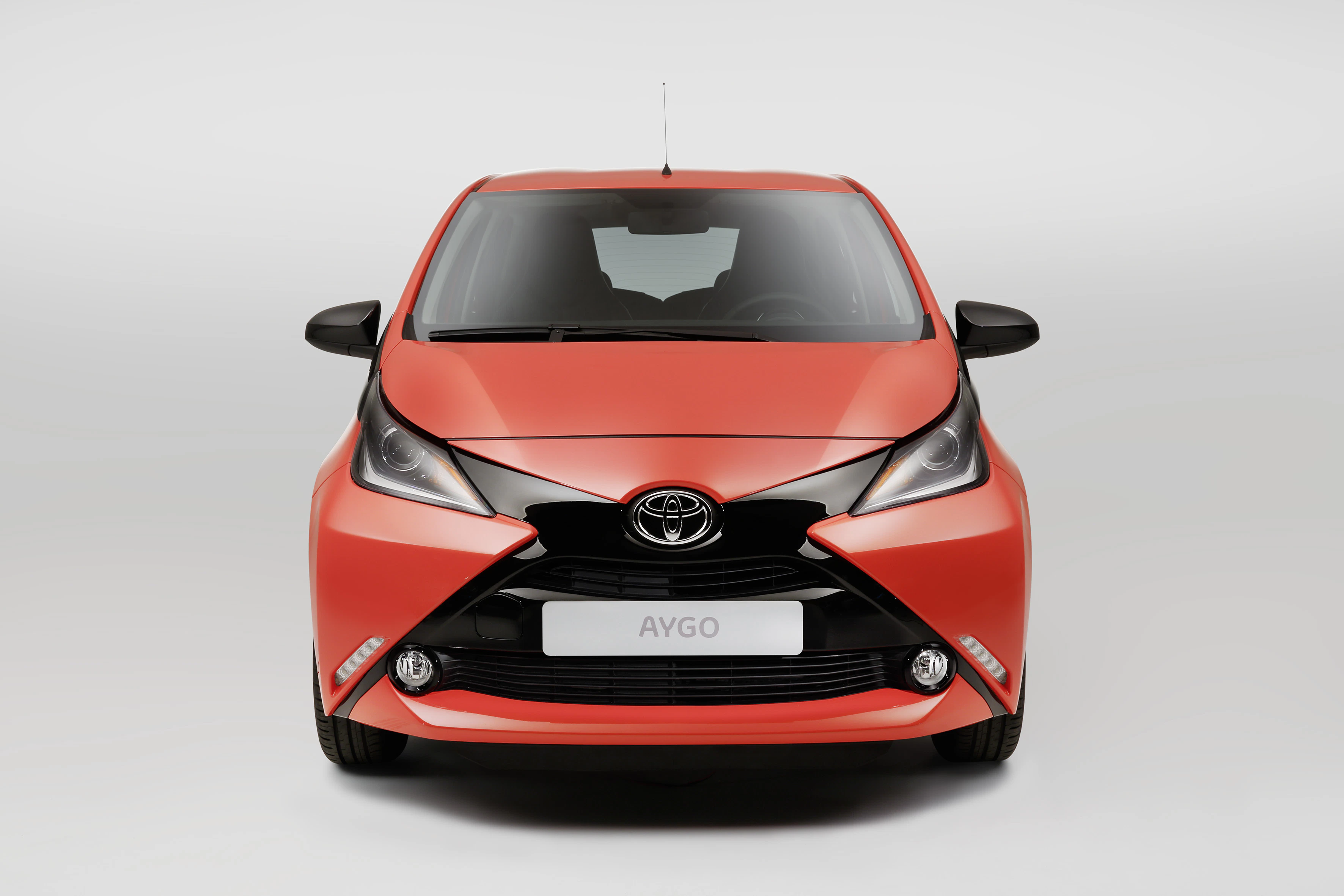 Roter Toyota Aygo, Frontansicht, mit modernem, kompaktem Design. Der Kühlergrill und die Scheinwerfer sind markant gestaltet.