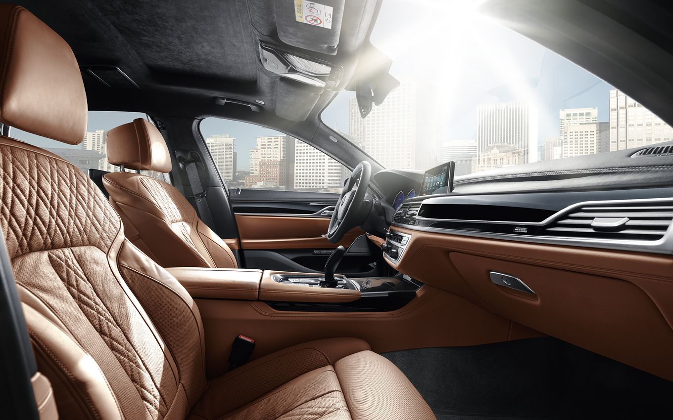 Luxuriöser Autoinnenraum mit braunen Ledersitzen, modernem Armaturenbrett und Stadtblick durch die Fenster im Hintergrund.