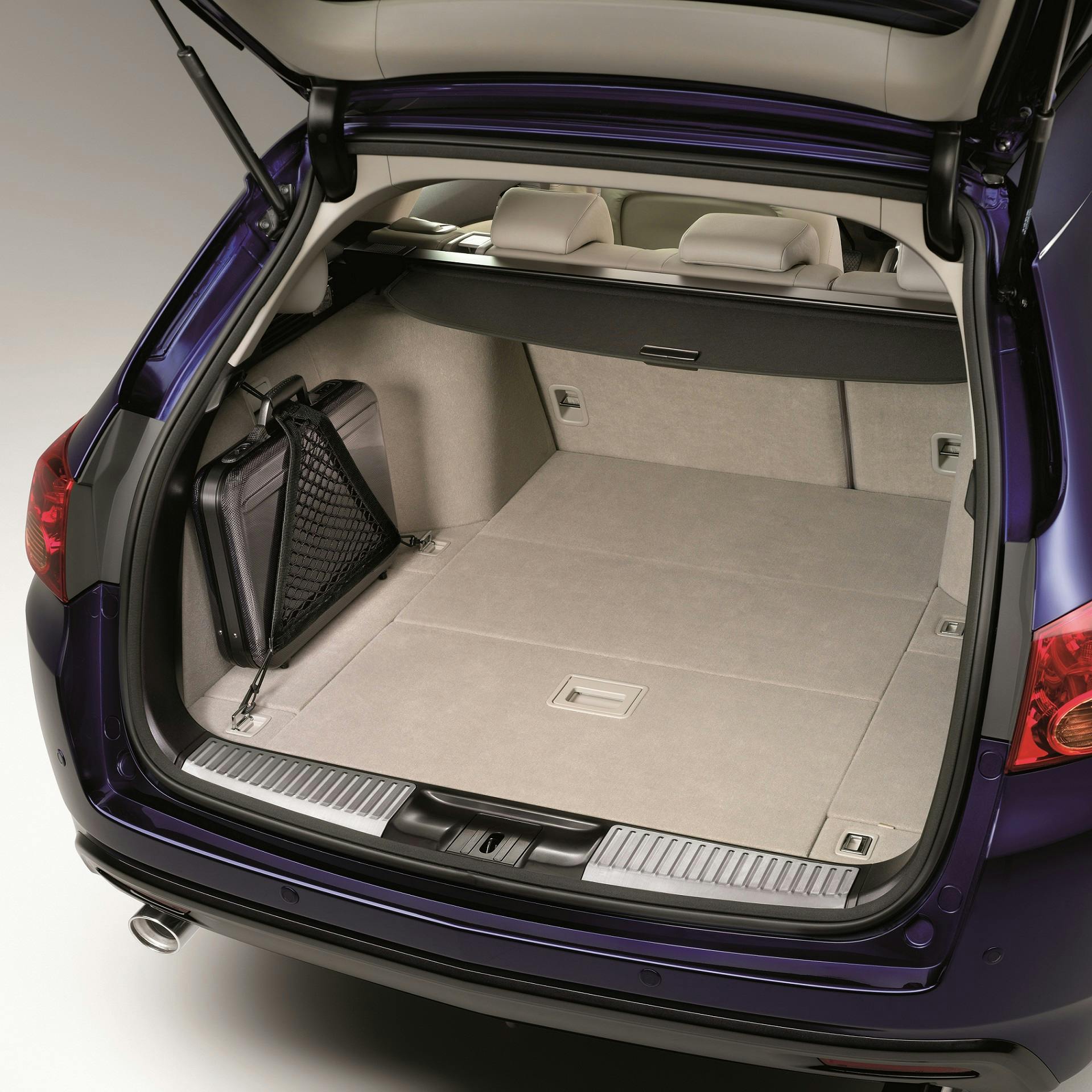 Offener Kofferraum eines dunkelblauen Autos mit hellem Innenraum und einer schwarzen Tasche auf der linken Seite.