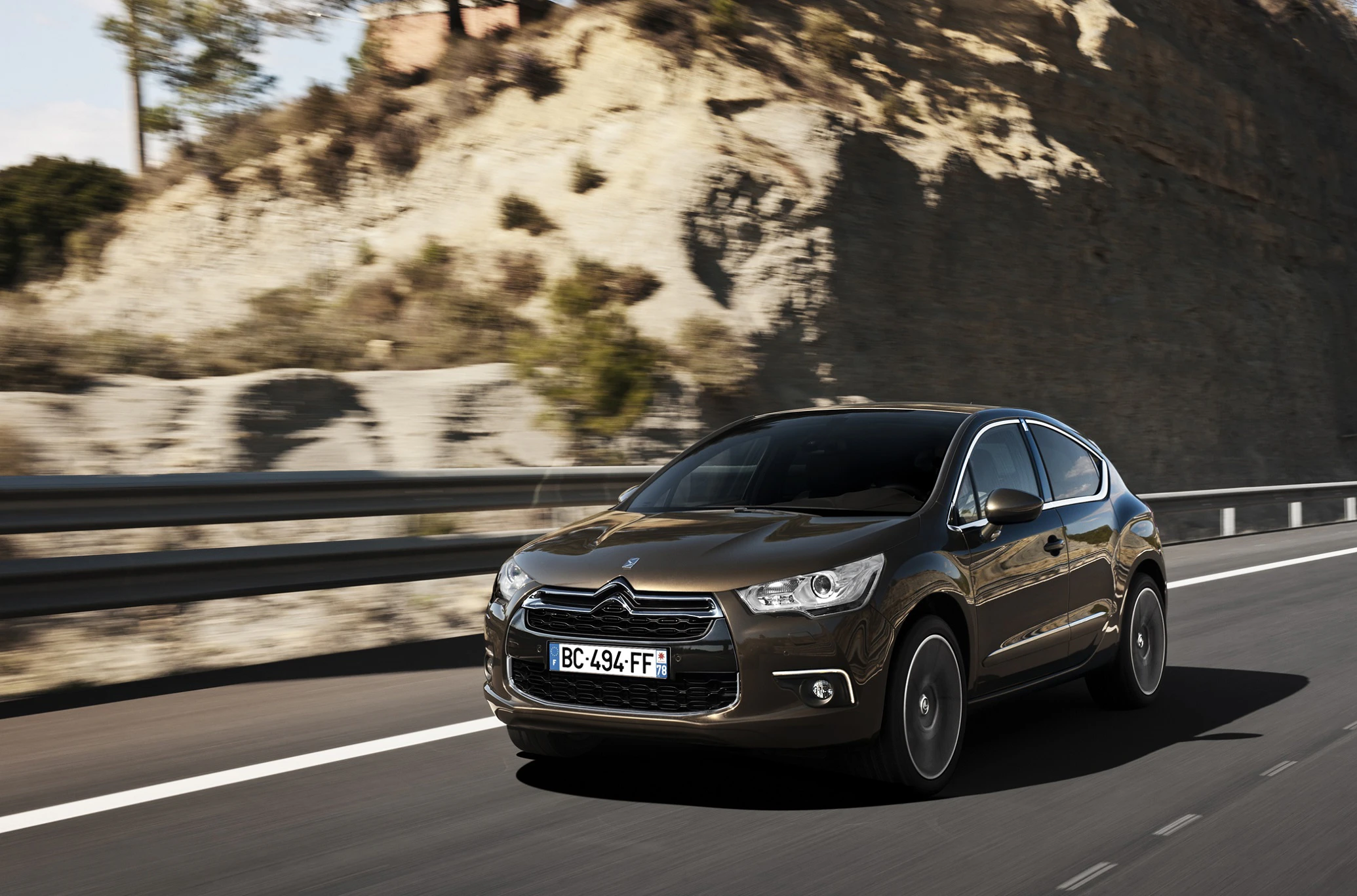 Schwarzer Citroën DS4 fährt auf einer Landstraße vor einer felsigen Landschaft bei sonnigem Wetter.