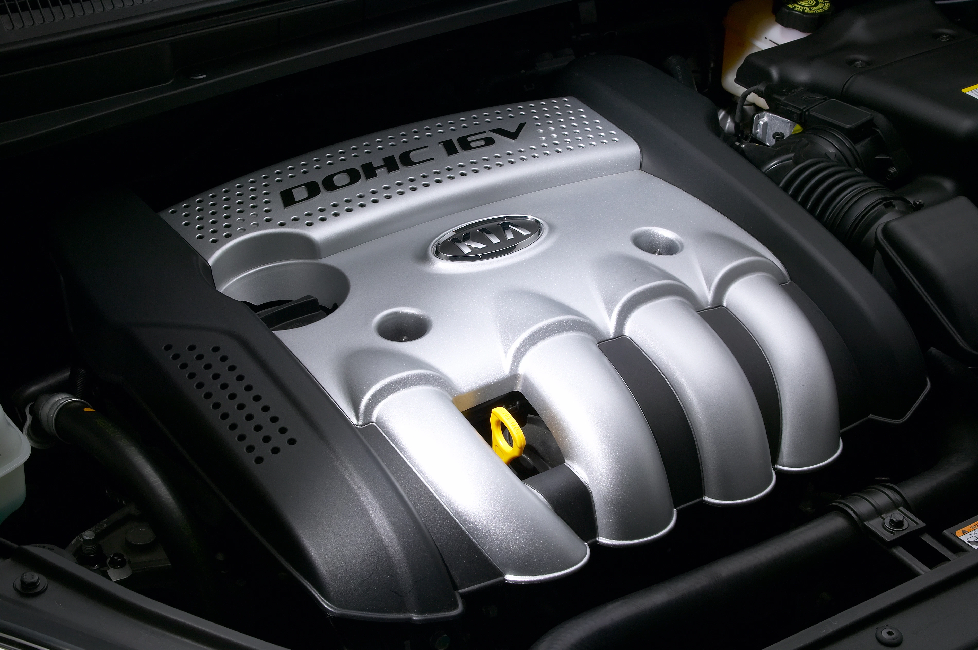 Motorraum eines Autos mit einem silbernen DOHC 16V-Motorabdeckung, Markenlogo sichtbar.