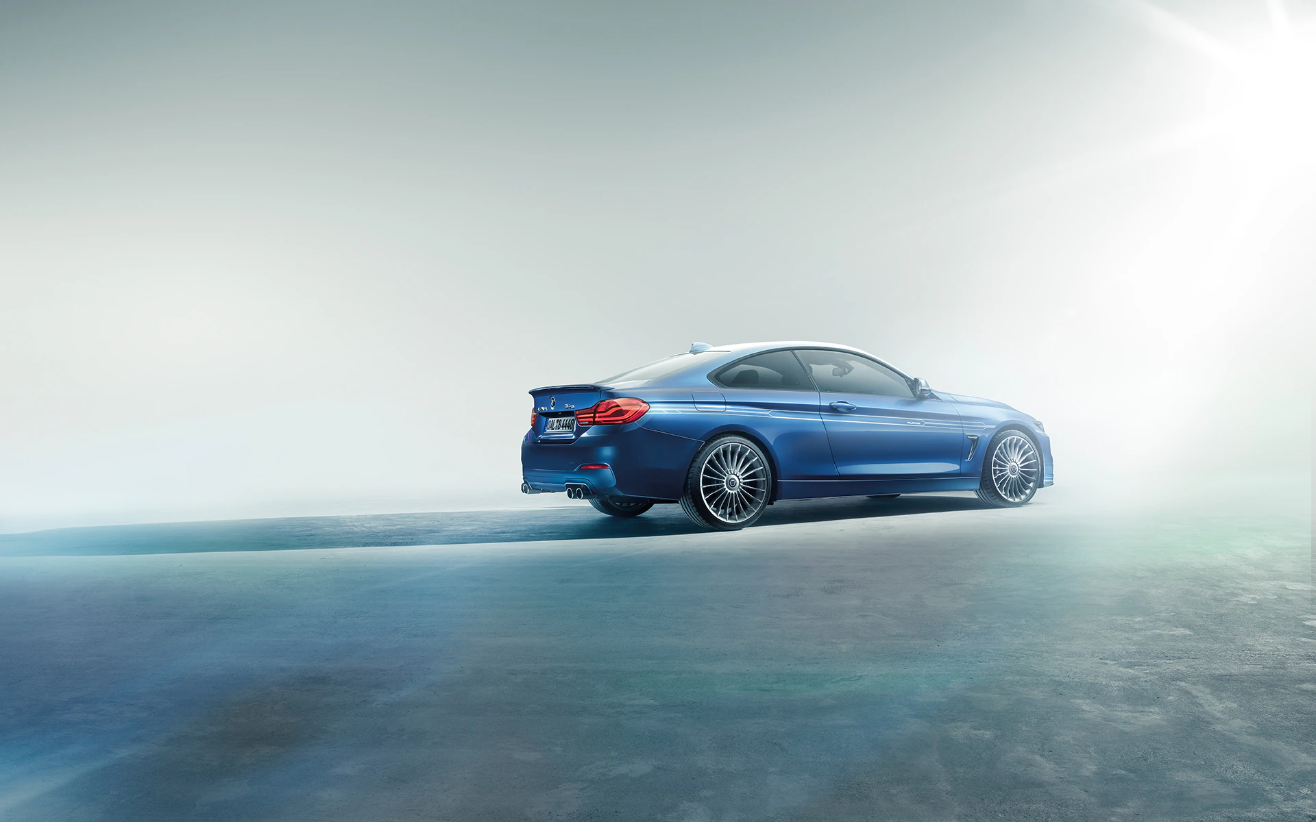 Blaues Sportcoupé auf einer leeren Straße mit hellem Hintergrund und dramatischer Beleuchtung, von der Seite fotografiert.
