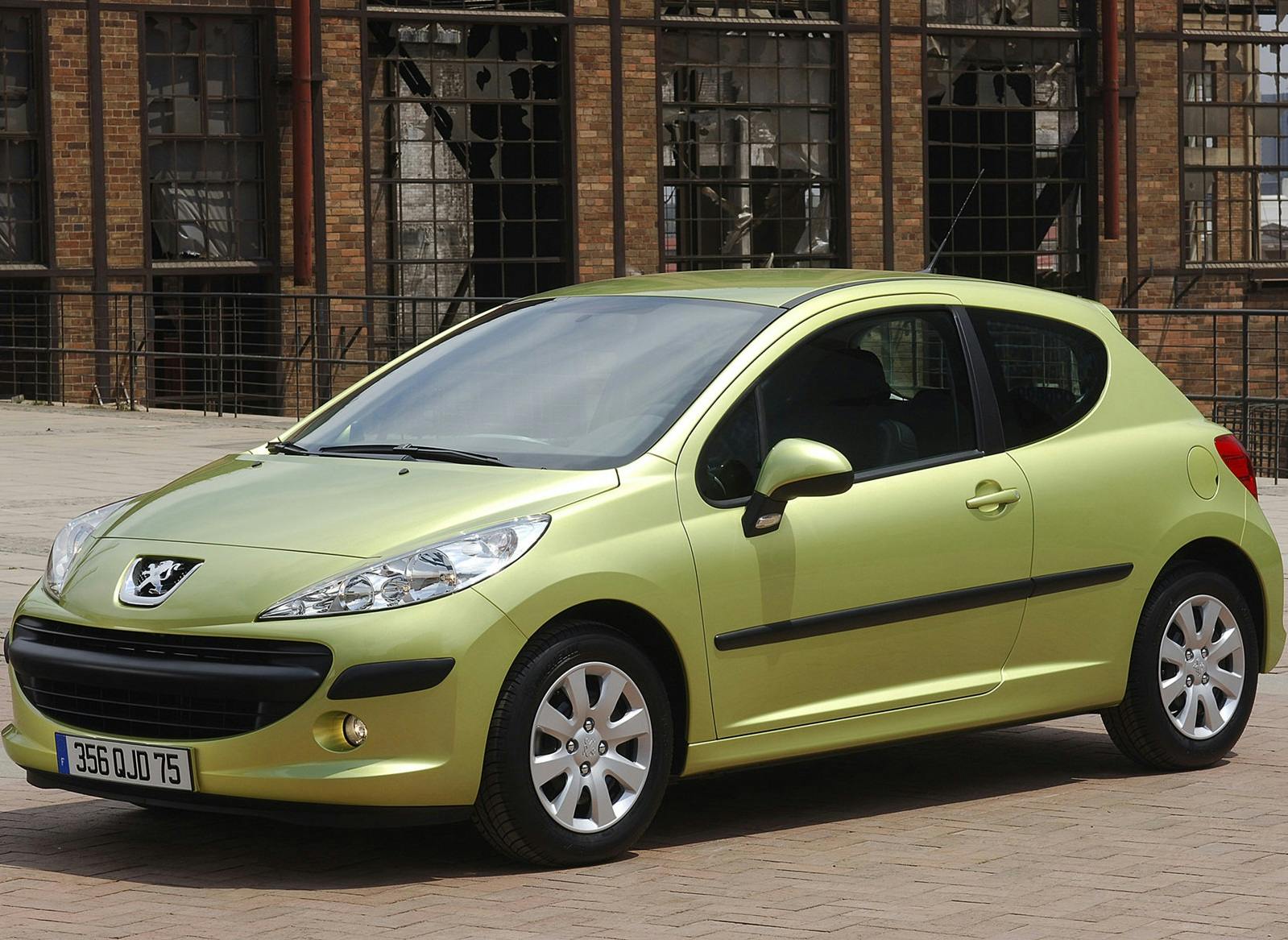 Grünes Auto, französisches Modell, parkt vor einem alten, ziegelsteinernen Industriegebäude.