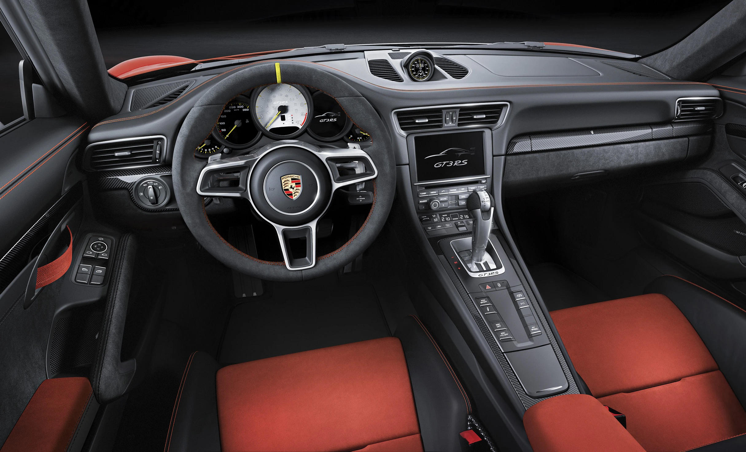 Innenraum eines sportlichen Autos mit Lederlenkrad, Tachometer, Touchscreen und rot-schwarzen Sportsitzen. Modernes, elegantes Design.