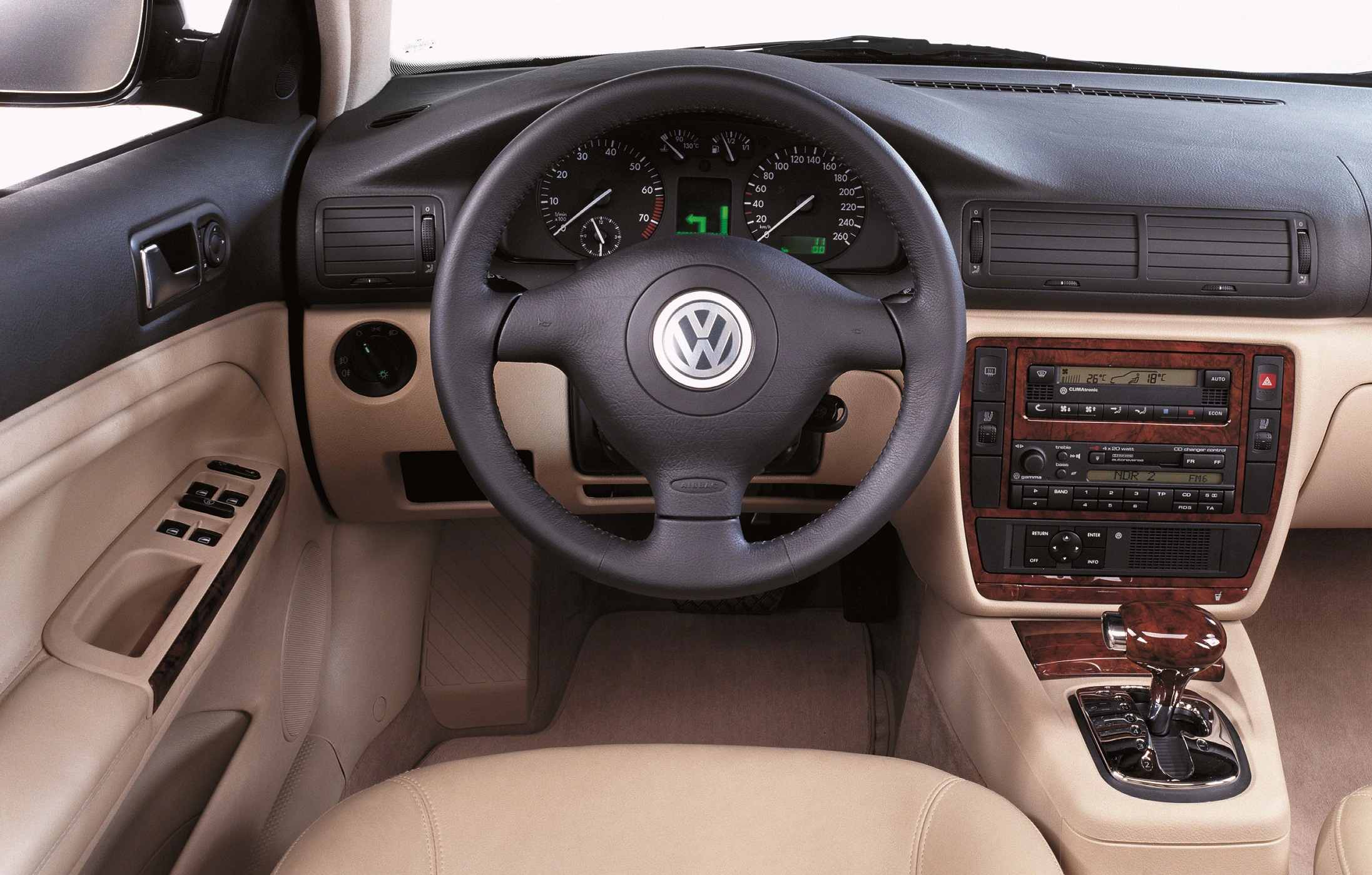 Innenraum eines VW-Autos mit Ledersitzen, einem Lenkrad mit VW-Logo, Tachometer, Mittelkonsole und Schaltknüppel.