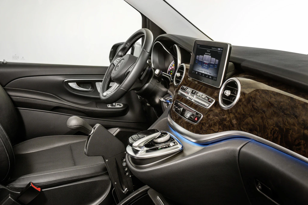 Innenraum eines modernen Autos mit Ledersitzen, Holzverkleidung, Multifunktionslenkrad und Touchscreen-Display auf der Mittelkonsole.