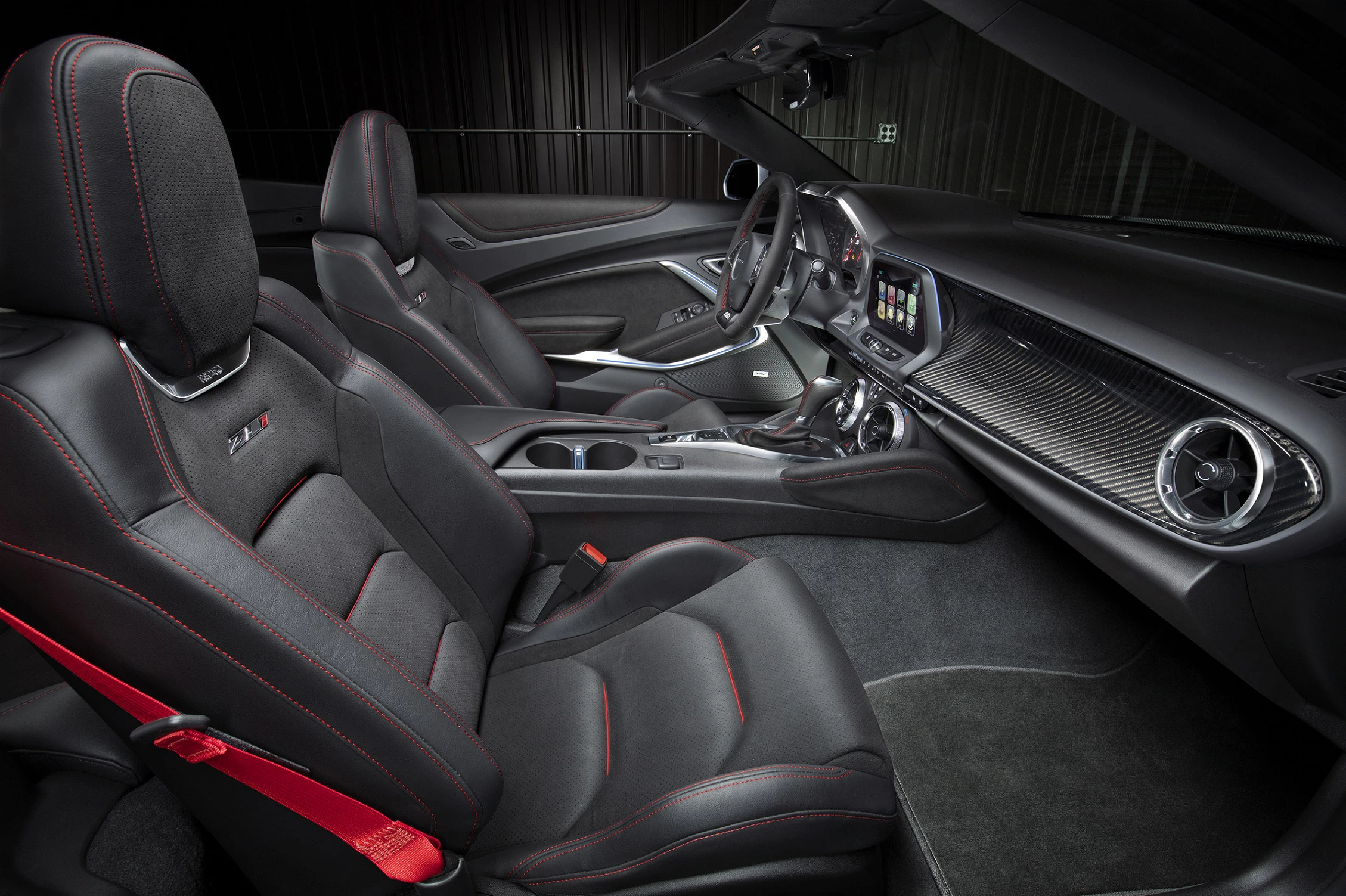 Innenraum eines modernen Sportwagens mit schwarzem Lederinterieur, roten Nähten und einem High-Tech-Armaturenbrett.