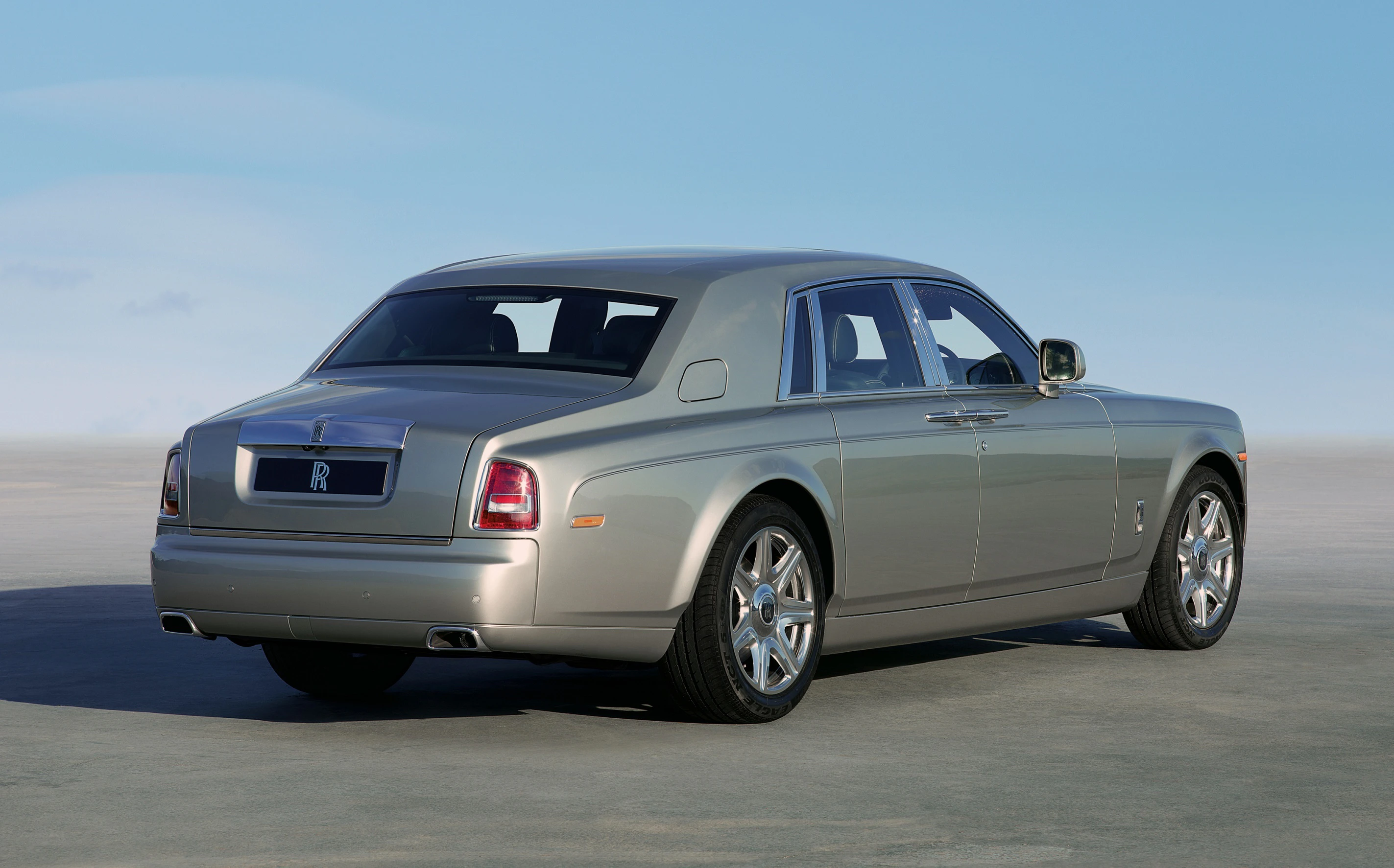 Luxuslimousine in silberner Farbe auf einer offenen Straße, mit blauen Himmel im Hintergrund. Elegantes Design mit glänzenden Felgen.