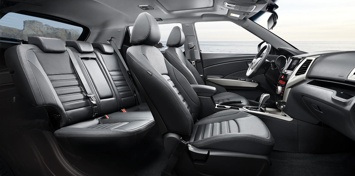 Innenraum eines modernen Autos mit schwarzen Ledersitzen, Mittelkonsole und Blick nach draußen auf das Meer.
