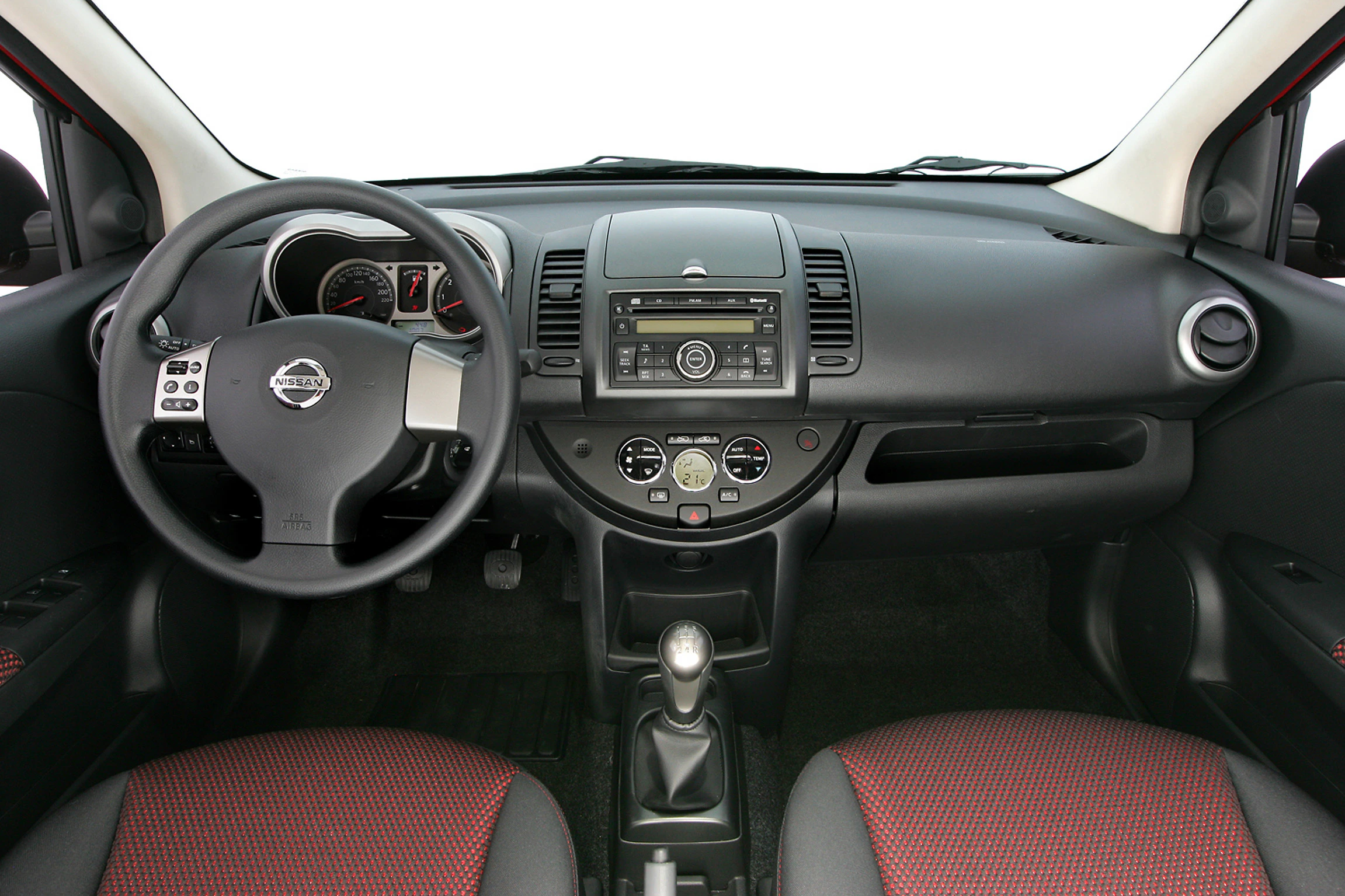 Innenraum eines Autos mit Lenkrad, Armaturenbrett und Schalthebel. Klassisches Design, schwarze und rote Sitze, moderne Bedienungselemente.