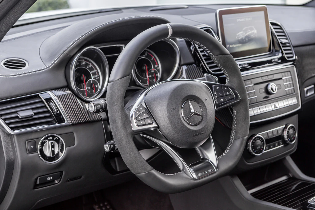 Innenraum eines Mercedes-Benz mit Lenkrad, Tachometer und Mittelkonsole. Moderne Interface-Anzeige und Bedienelemente erkennbar.