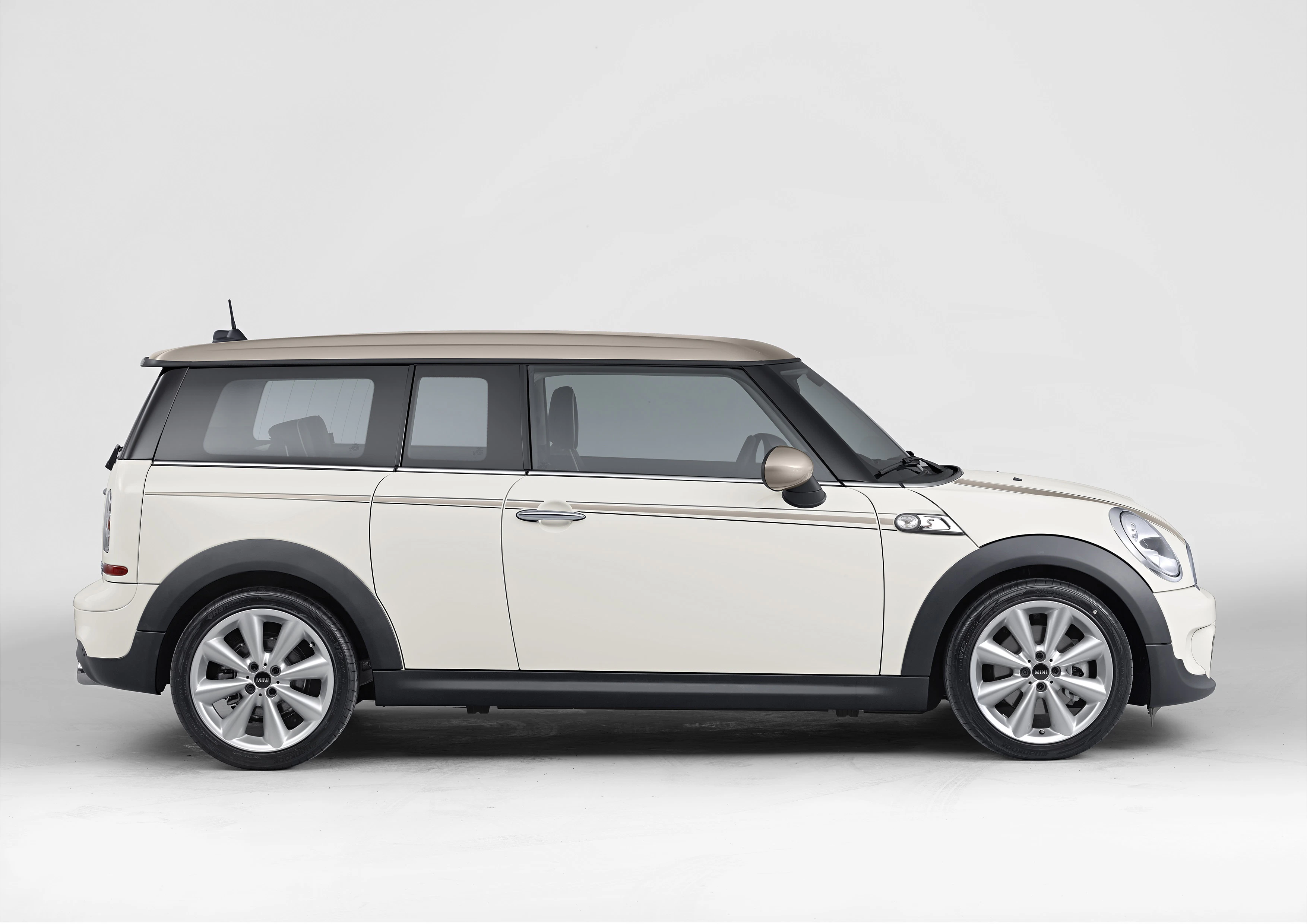 Seitenansicht eines weißen Mini Clubman mit braunem Dach, auf weißem Hintergrund.