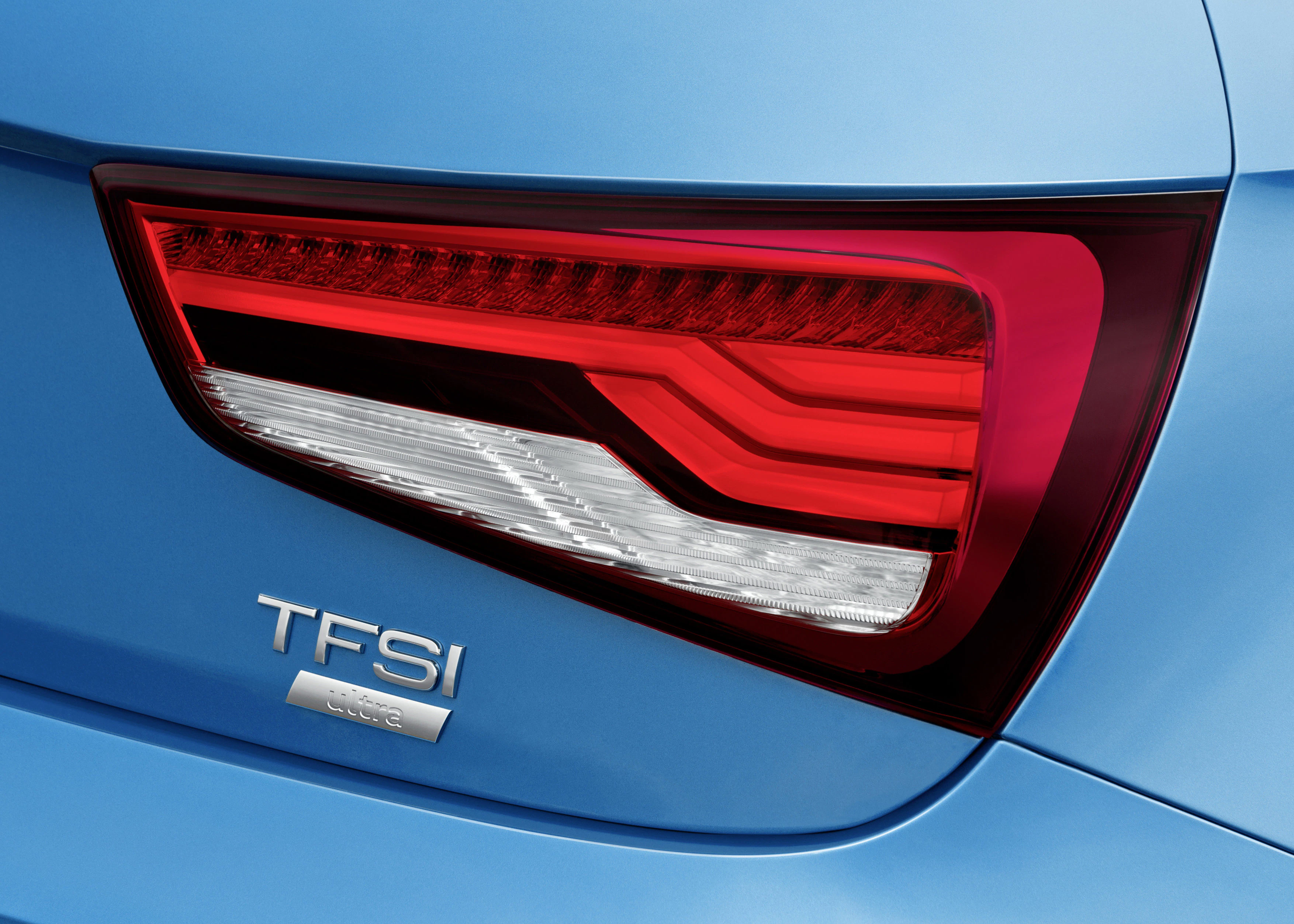 Rücklicht eines blauen Autos mit der Aufschrift "TFSI", stilvoll und modern gestaltet, mit roten und weißen Leuchtelementen.