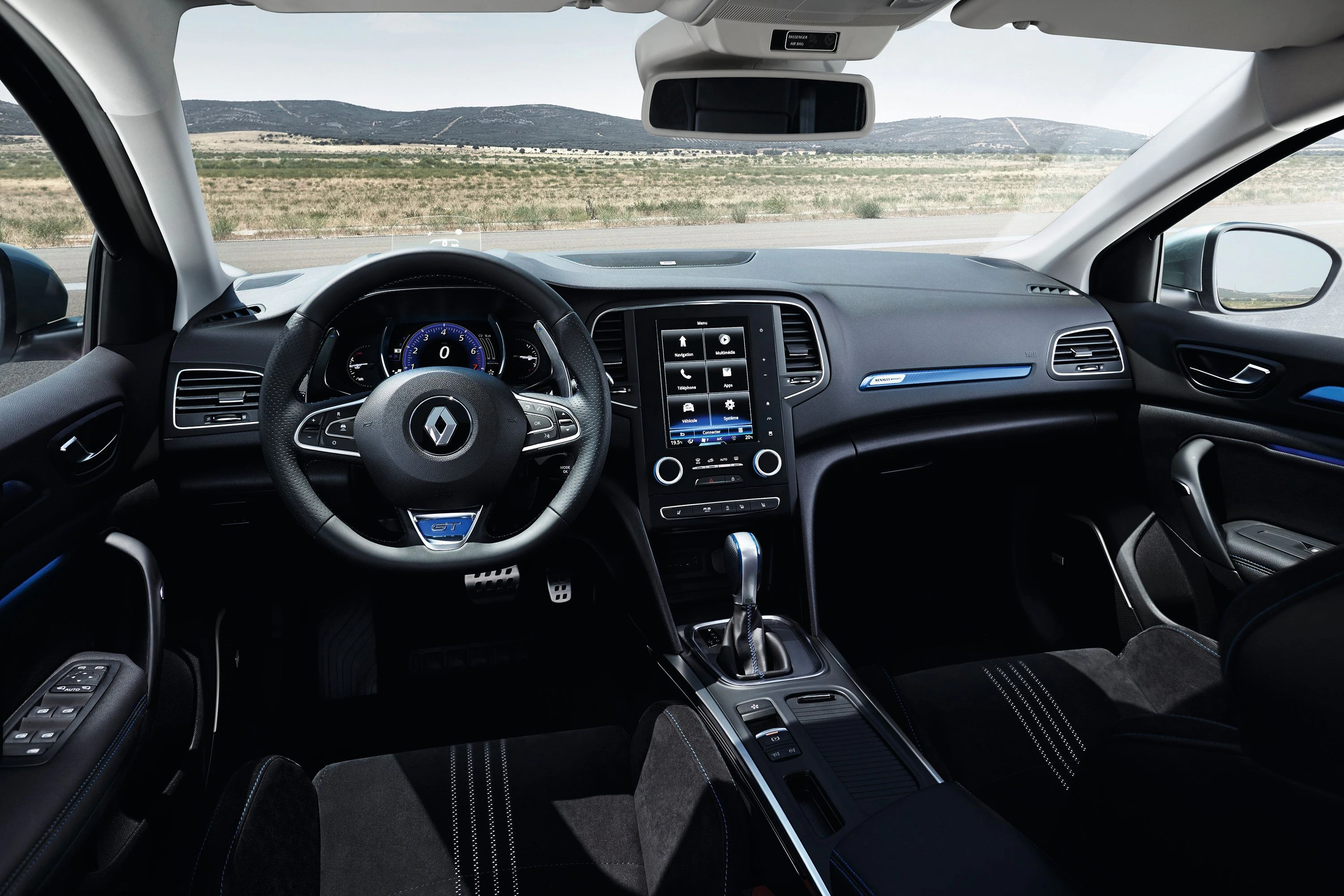 Innenraum eines modernen Autos mit einem digitalen Armaturenbrett, großem Touchscreen-Display und schwarzen Sitzen. Landschaft im Hintergrund.