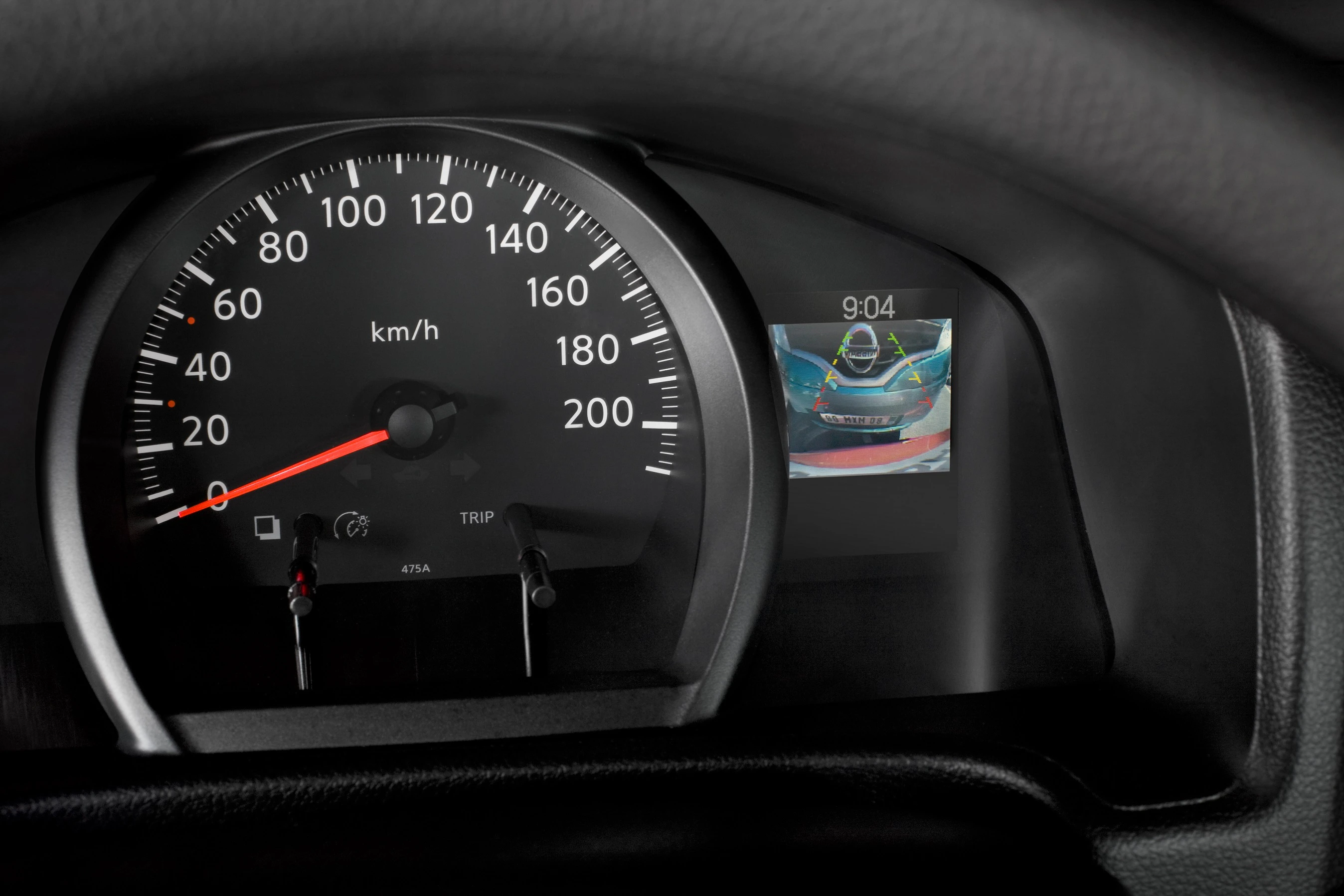 Tachometer eines Autos zeigt Geschwindigkeit in km/h; daneben ein Display mit Rückfahrkameraansicht. Geschwindigkeit: 0 km/h.